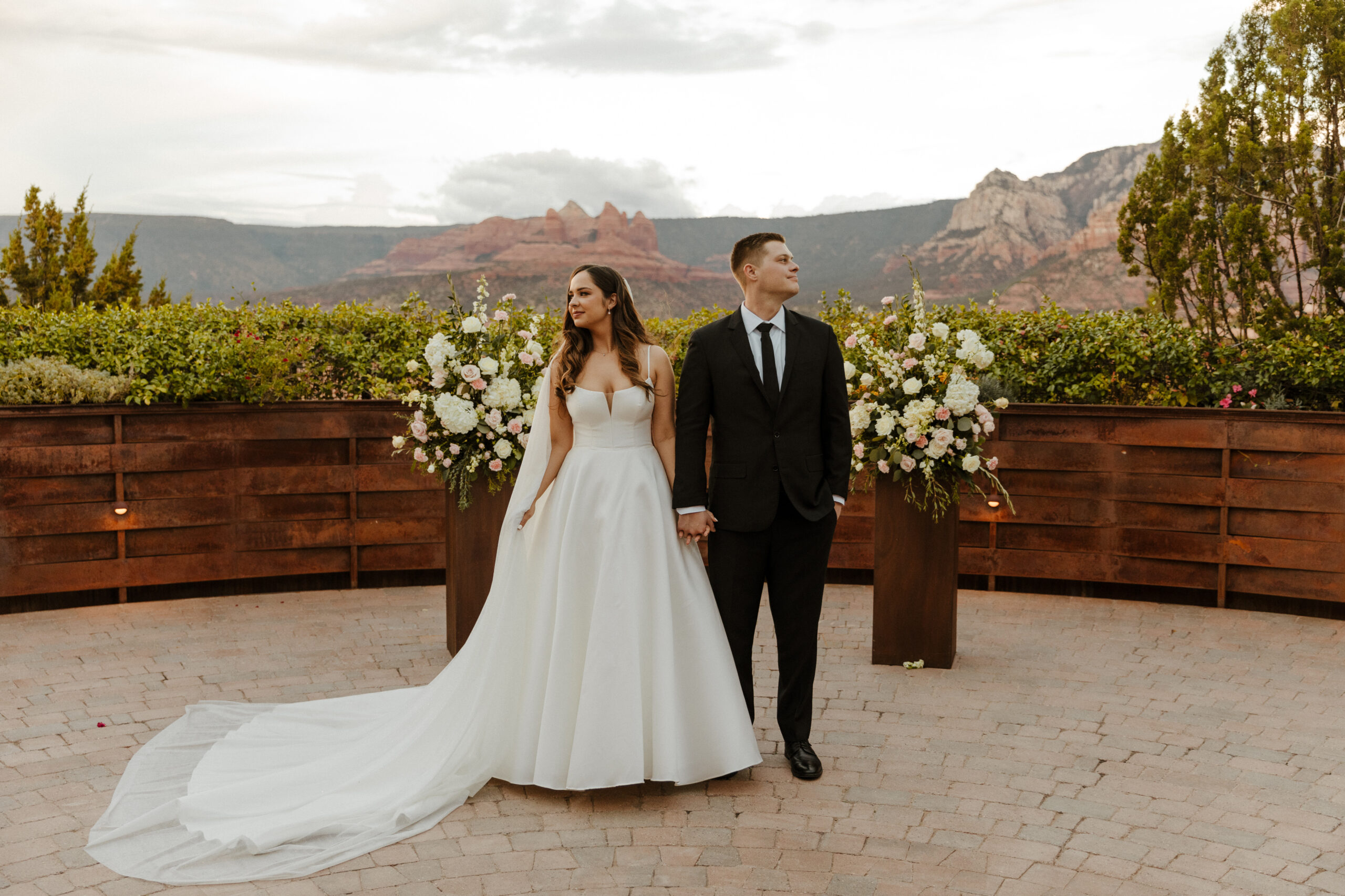 bride and groom holding hands at altar with sedona mountains in background 