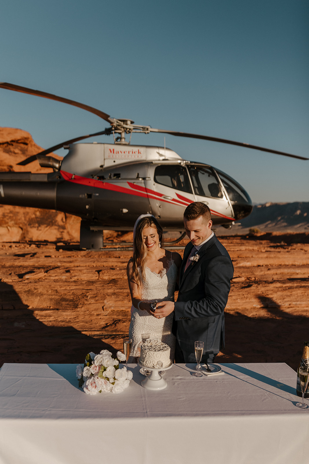 bridal couple cutting cake in front of helicopter