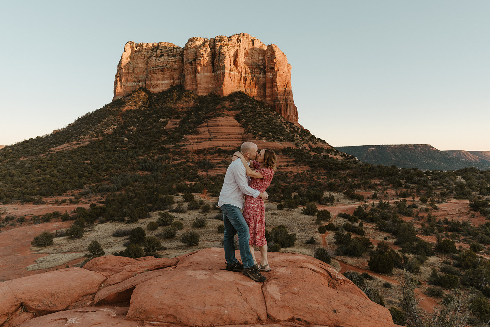couple kissing after arizona proposal with sedona landscape in background