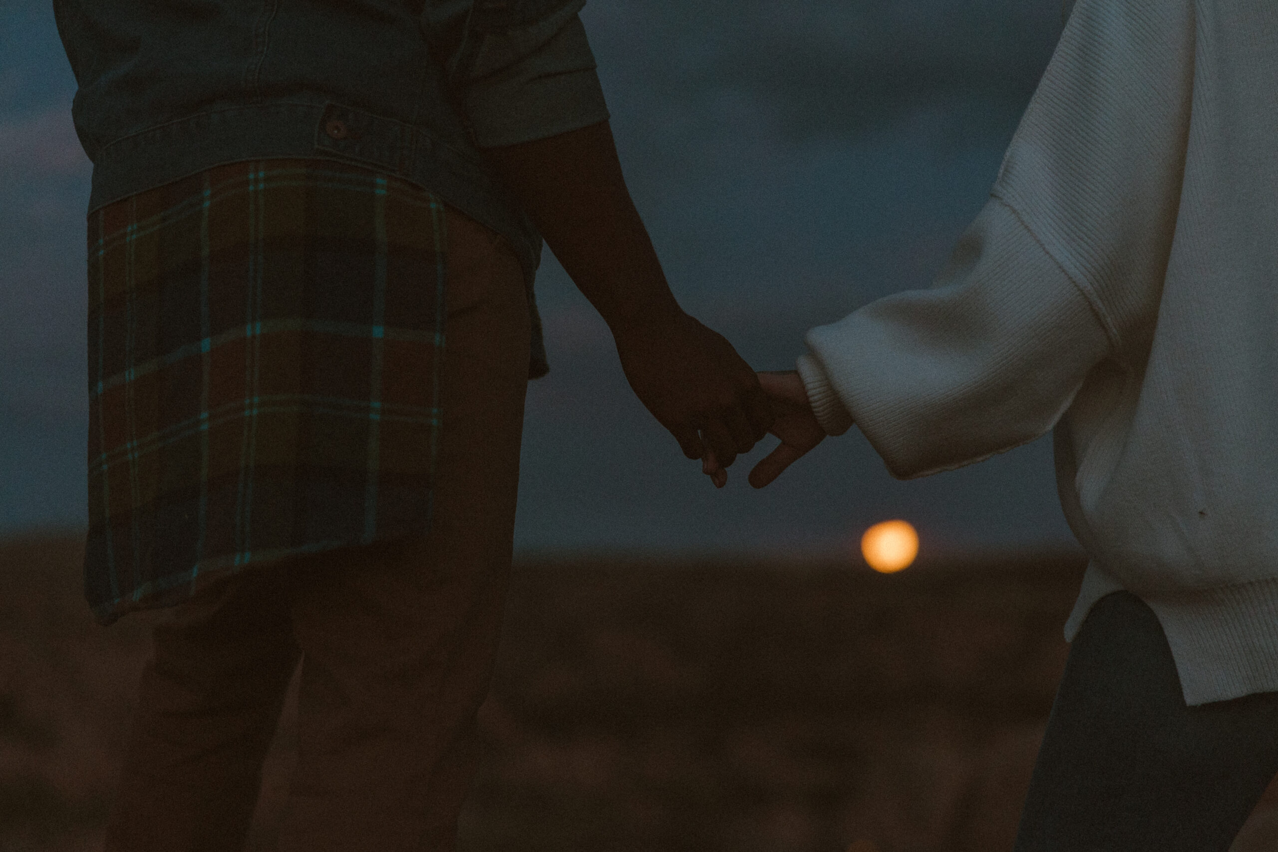 couple holding hands at sunset with the moon rising at watson lake in Arizona 