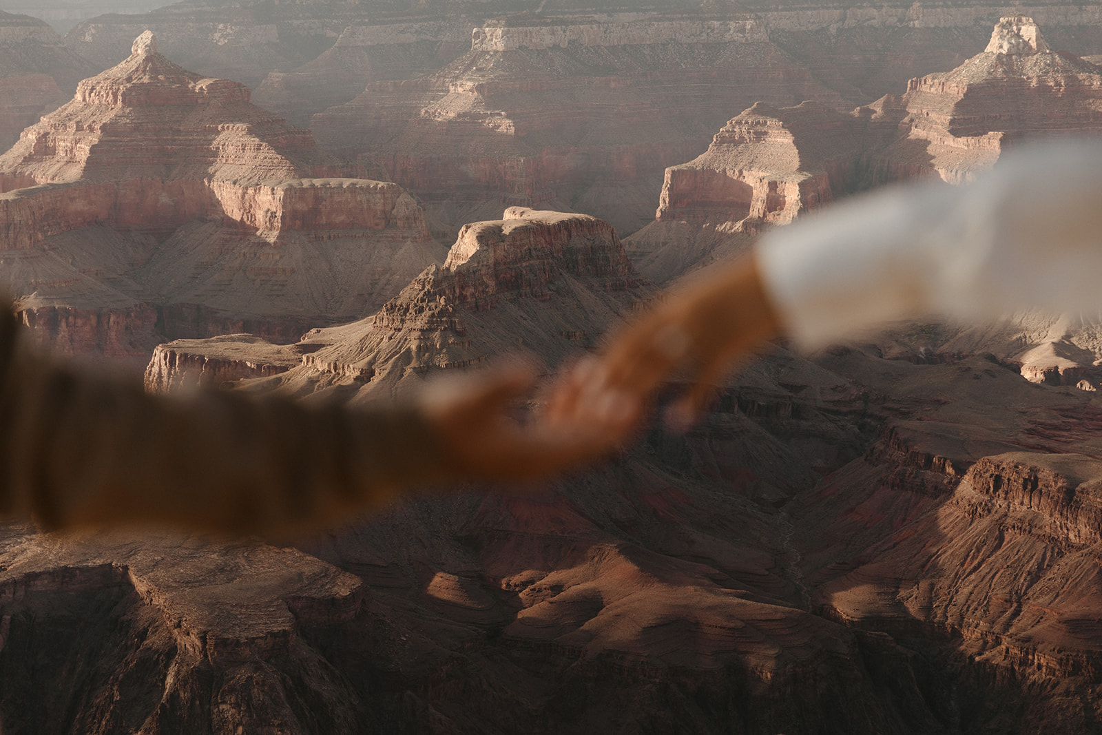 blurred hands reaching with Grand Canyon in focus