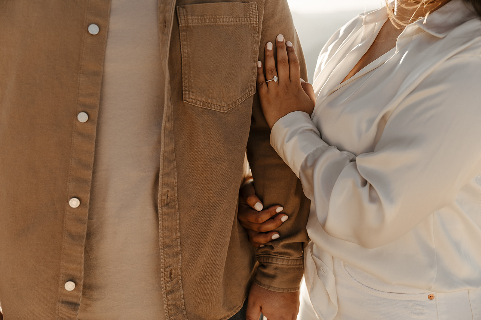 closeup of holding each others arms with engagement ring