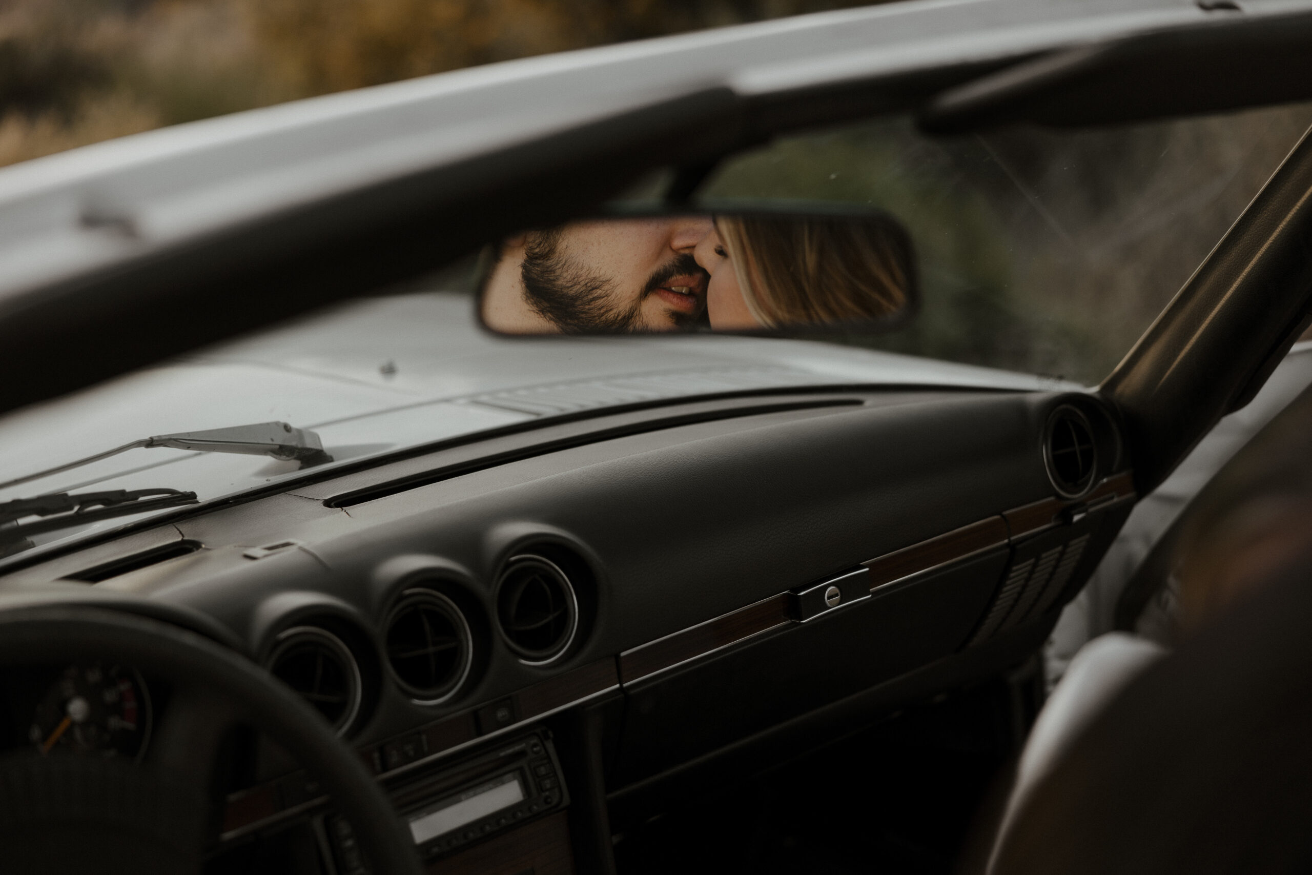 couple kissing in the rearview mirror for vintage car engagement photos
