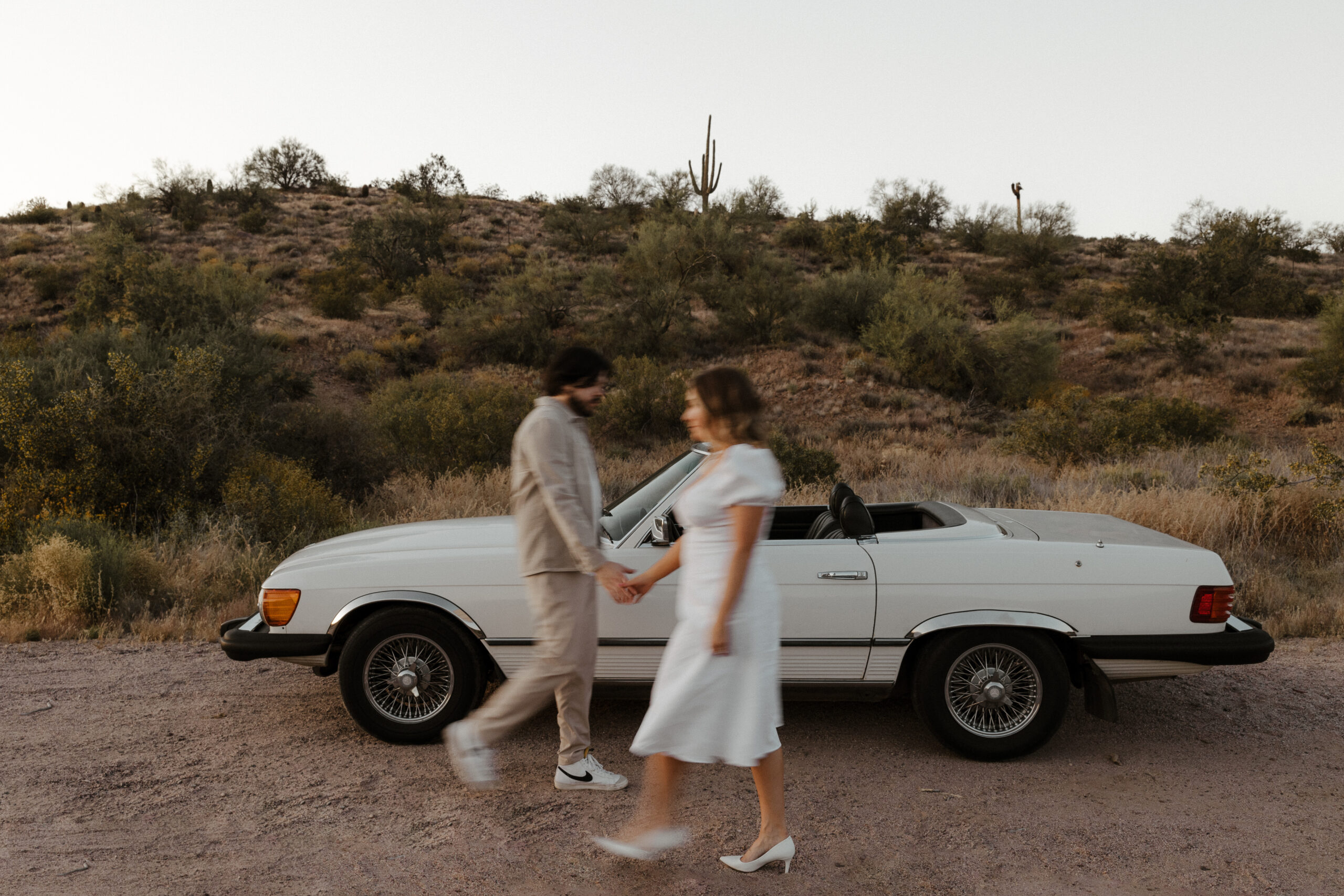 blurry photo of couple walking and holding hands for vintage car engagement photos