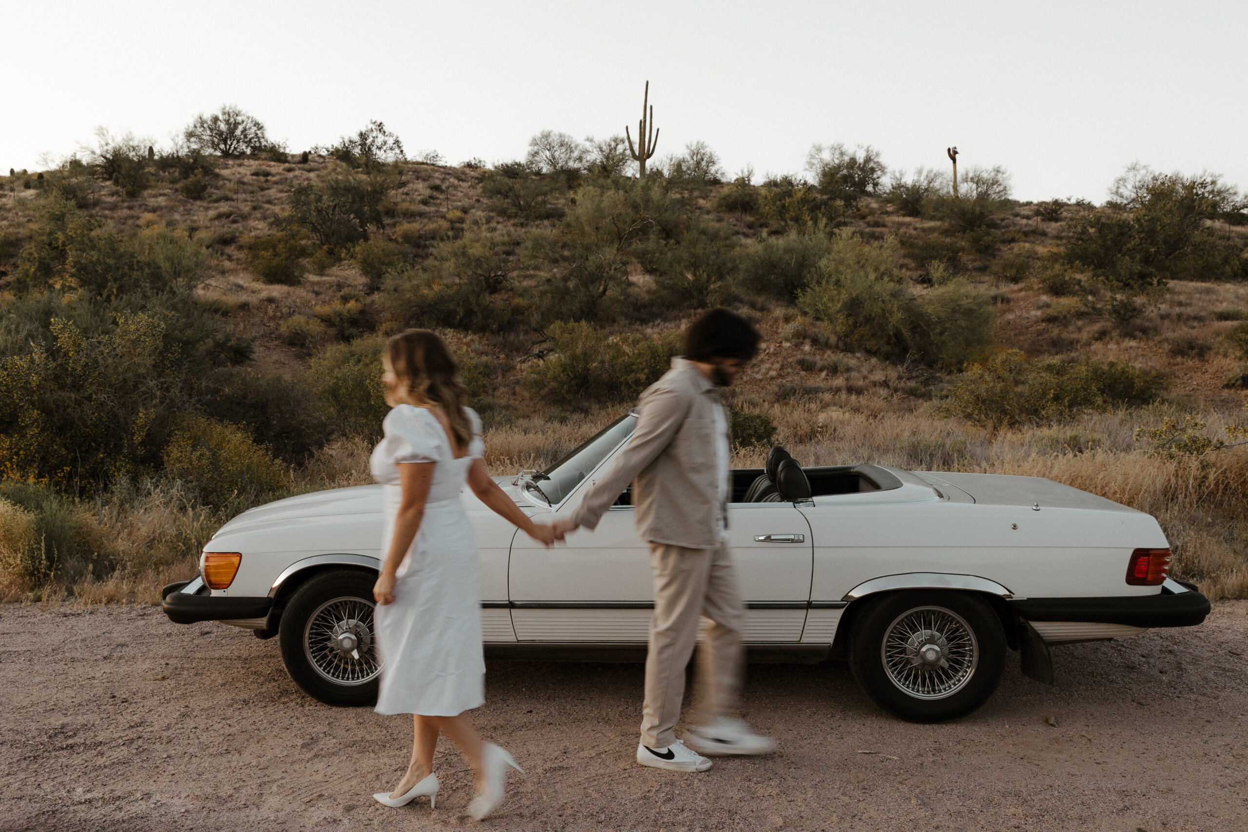 blurry photo of couple walking and holding hands for vintage car engagement photos