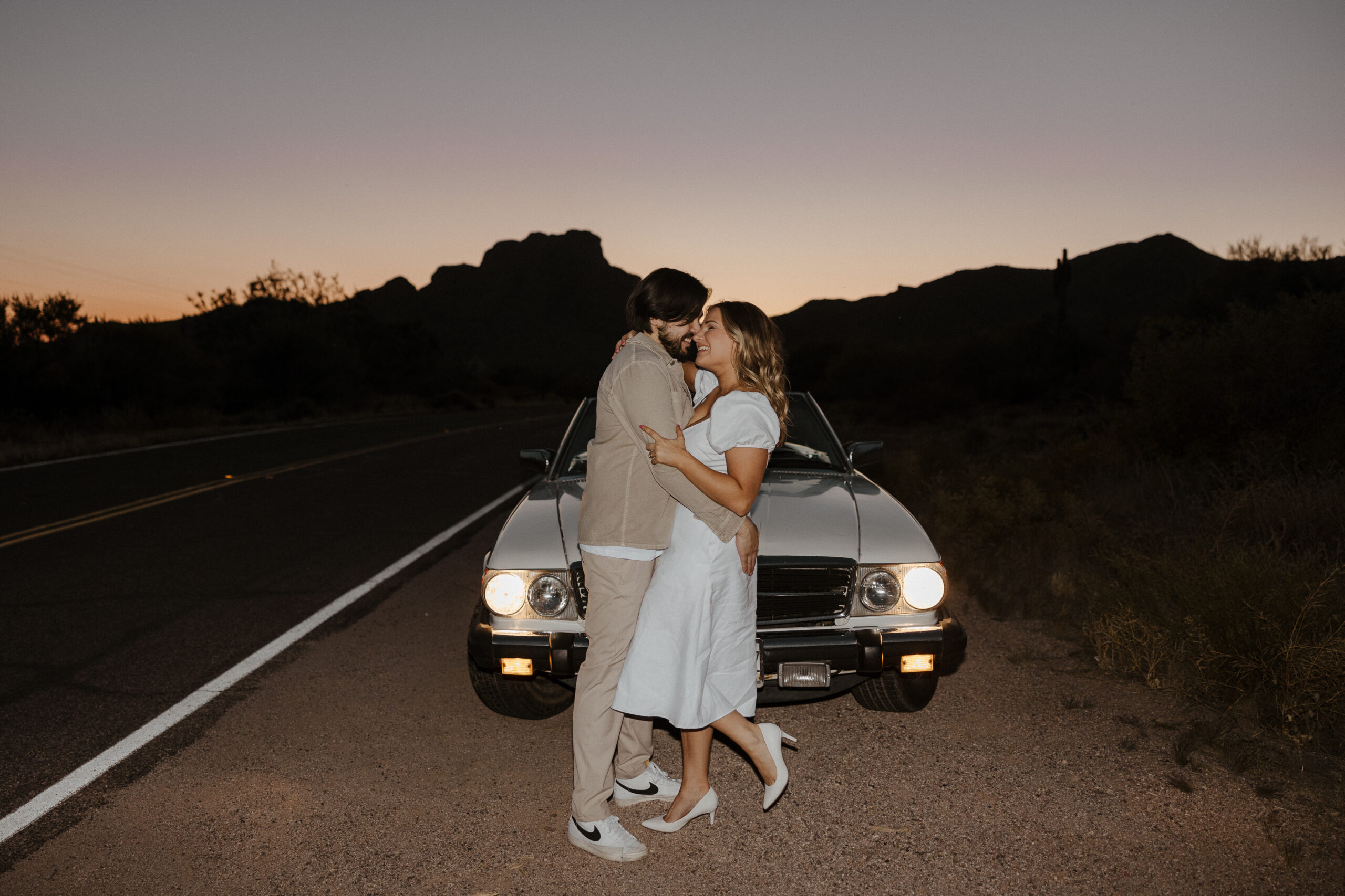 couple holding each other in front of the car at sunset for vintage car engagement photos