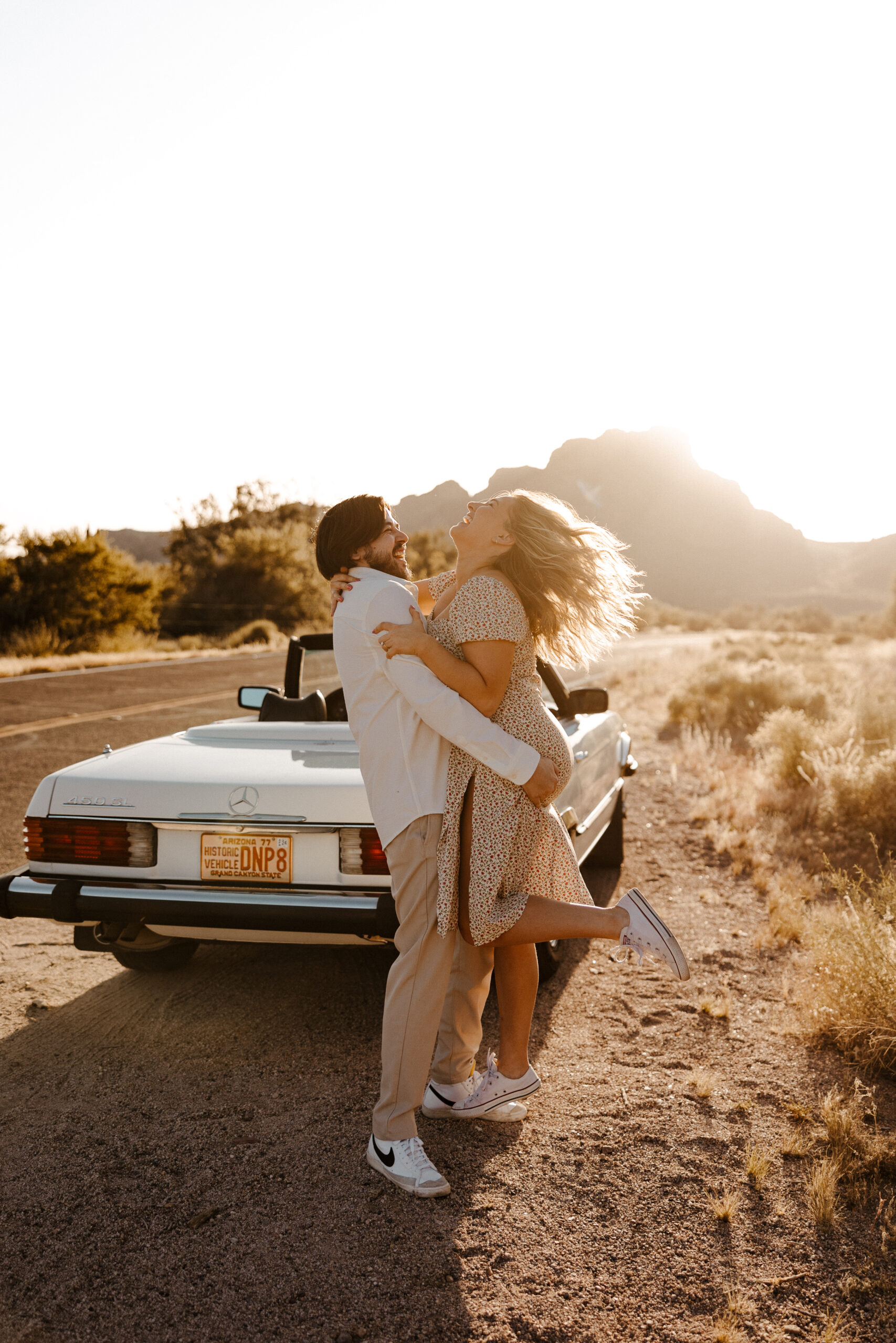 finace picking up other fiance and laughing at the back of car for vintage car engagement photos
