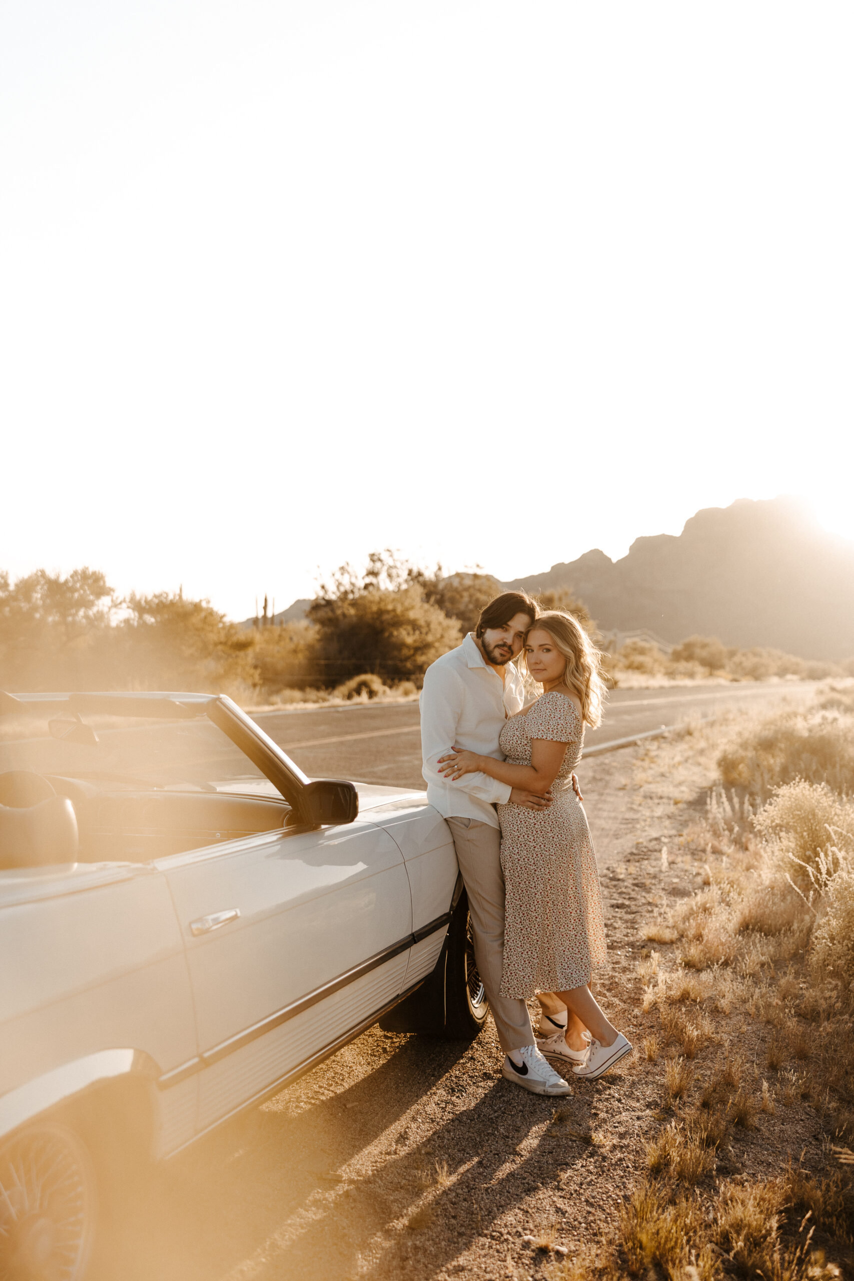 newly engaged couple holding each other standing by vintage car