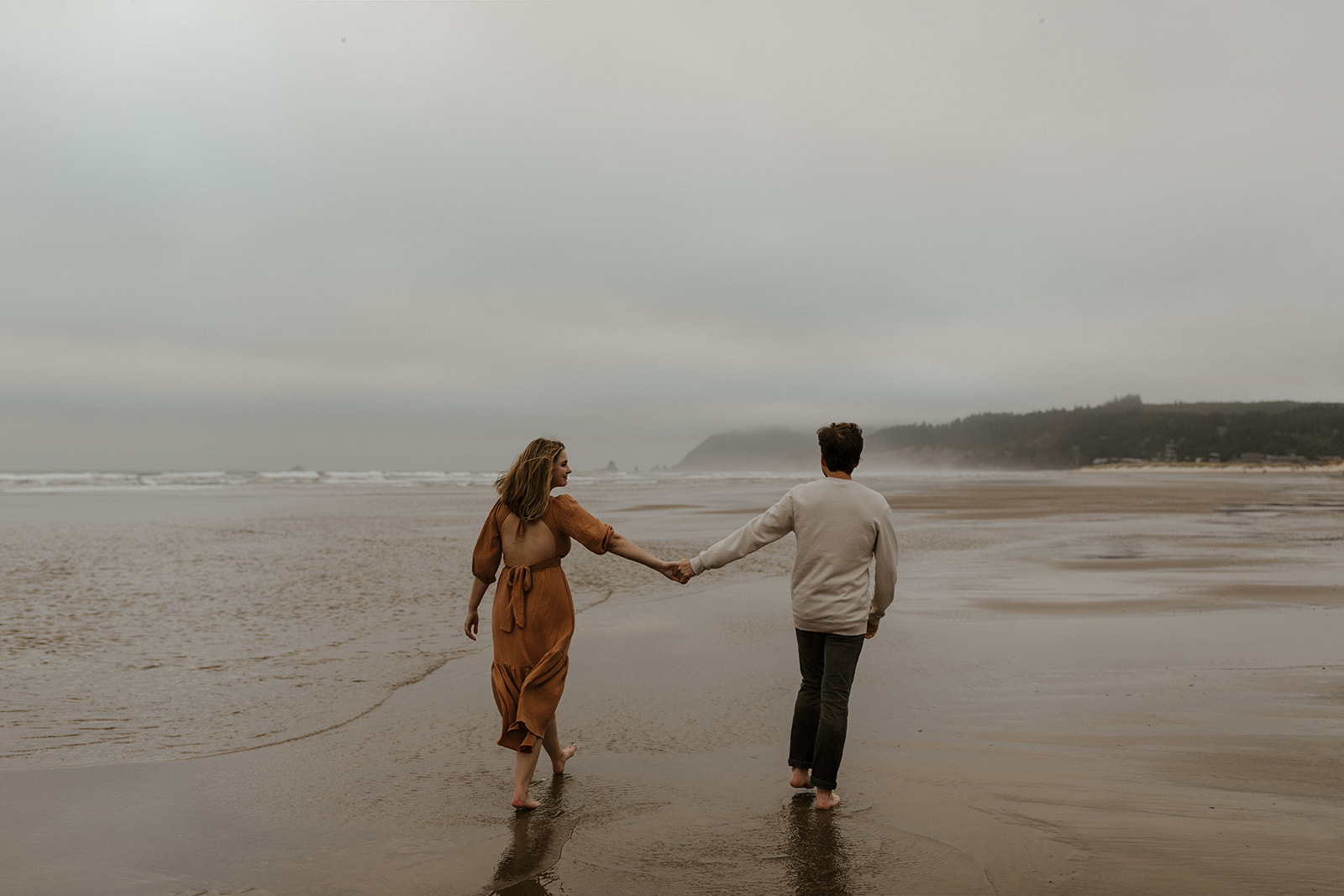 couple walking holding hands on the beach 