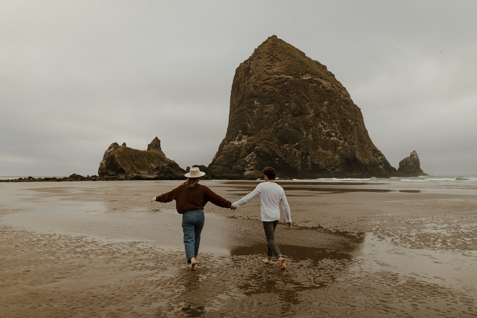 cannon beach engagement couple with haystack rock in the background