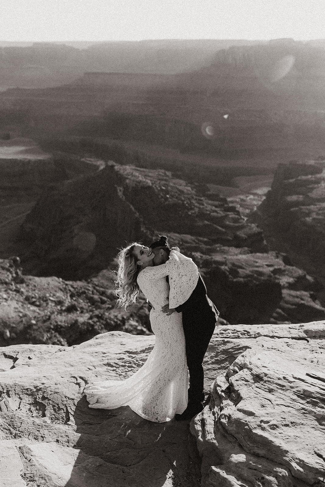 black and white of bridal couple kissing at moab elopement with scenery in the background