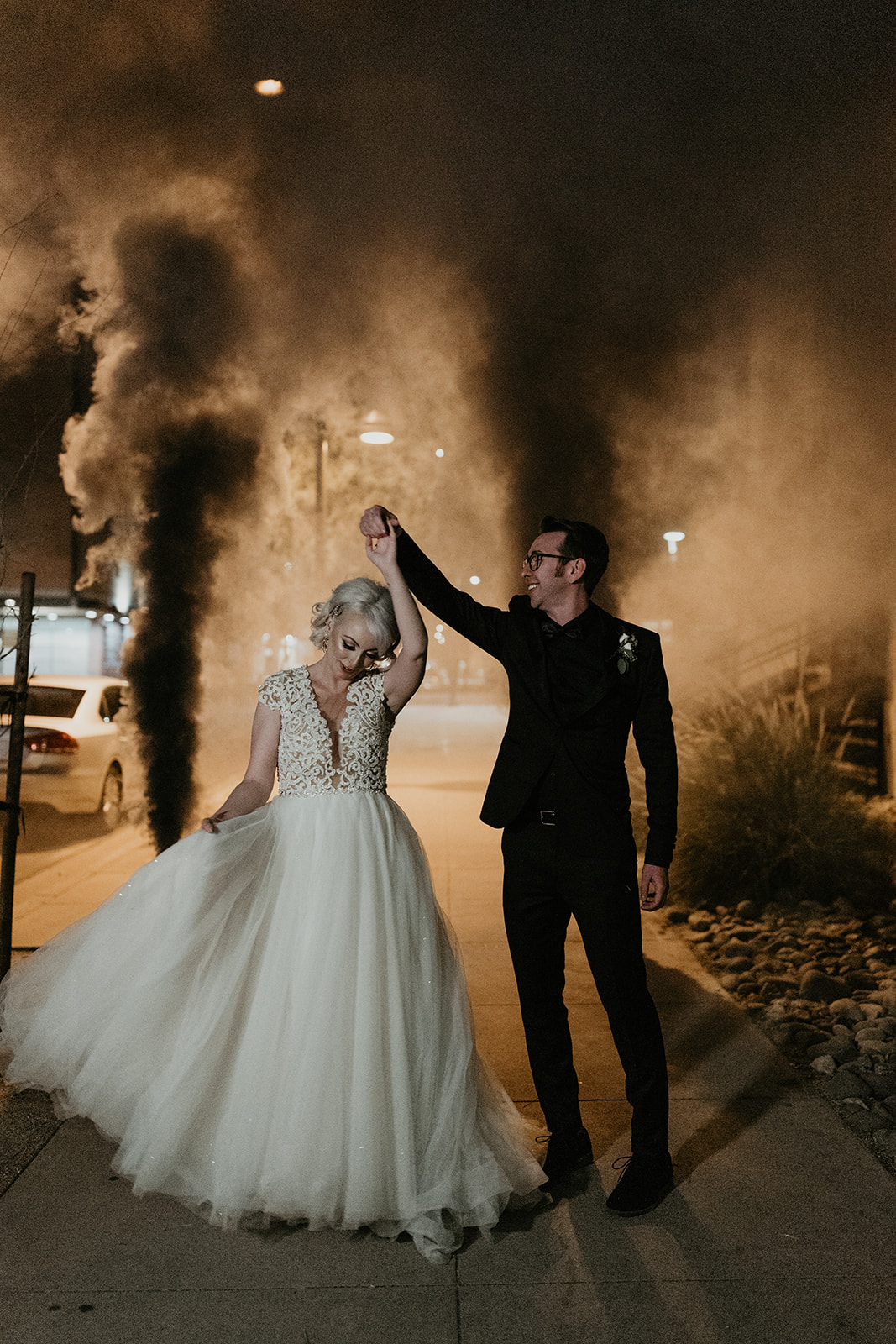 bridal couple dancing with black smoke bombs going off behind them 