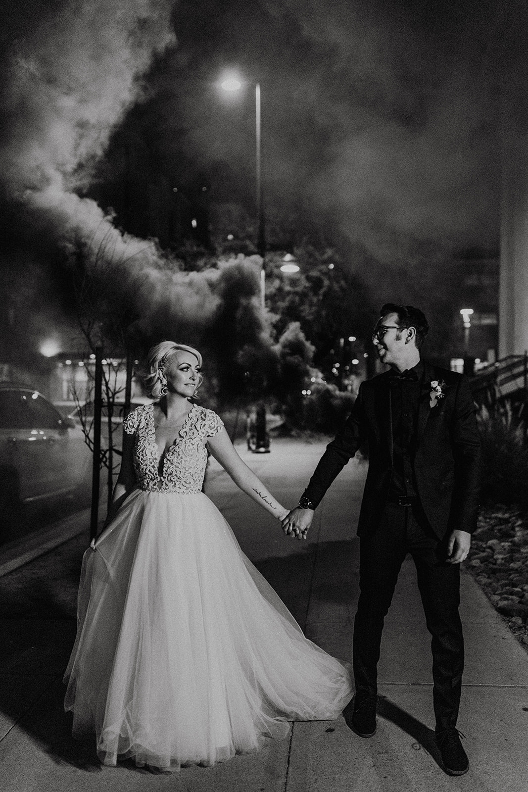 black and white spooky bridal couple portrait with black smoke bombs going off behind them 