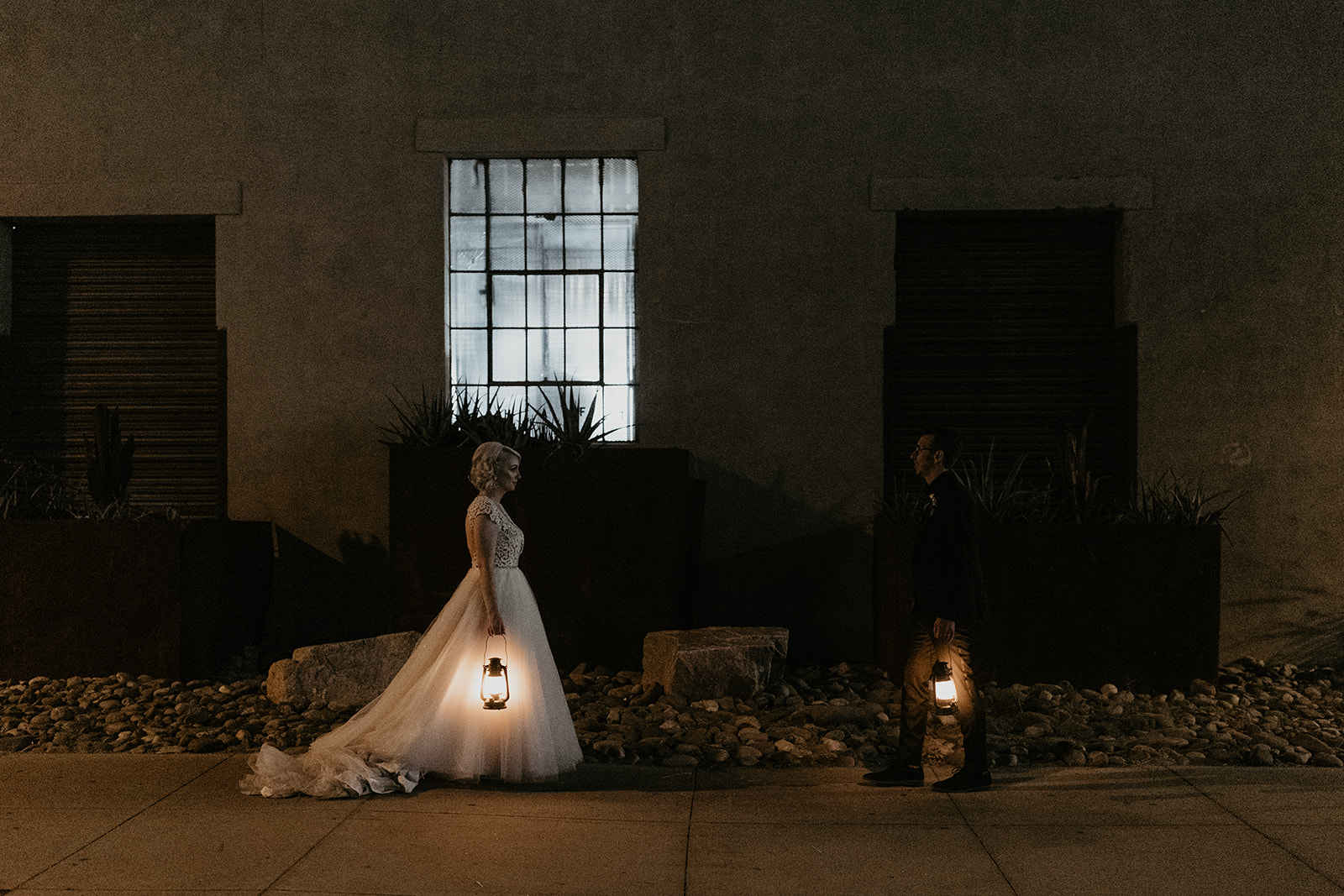 bride in groom outside in the dark facing each other holding lanterns 