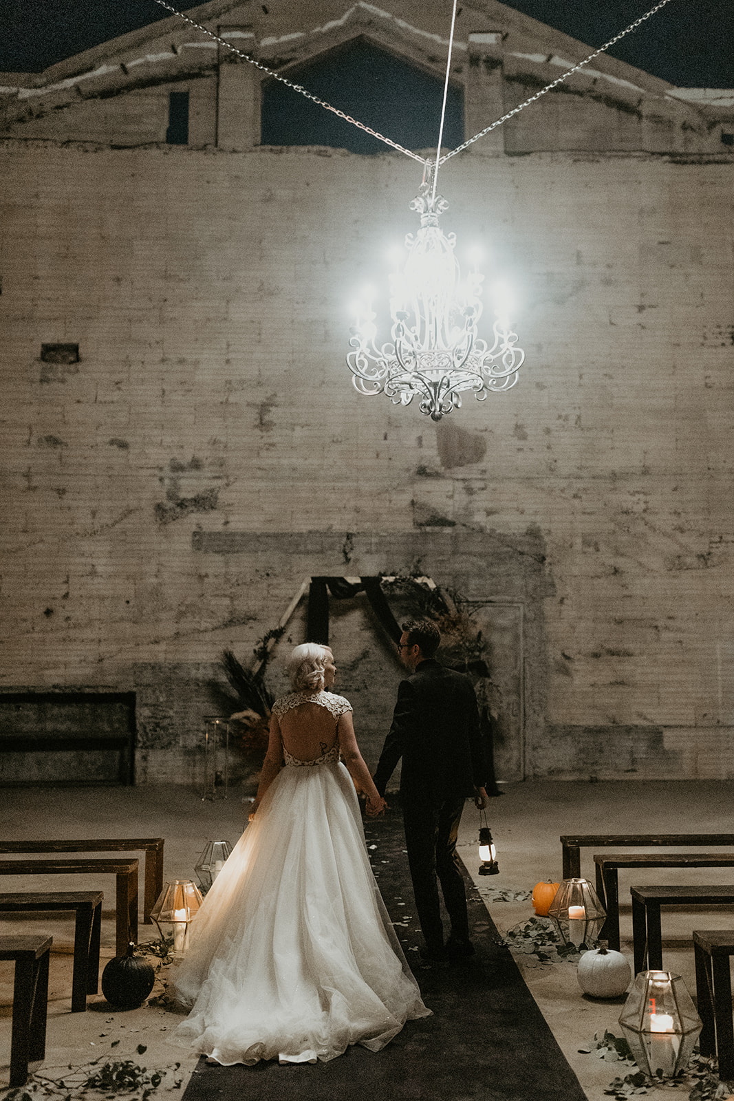bridal couple portrait in ceremony space holding the lanterns with the altar in the background