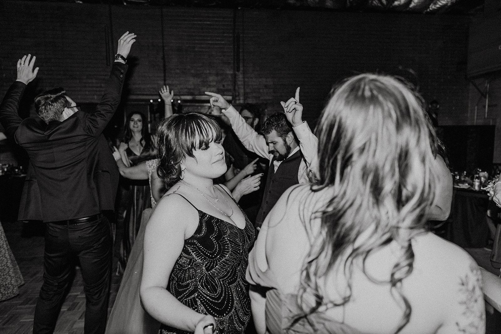 black and white candid of wedding guests dancing at reception