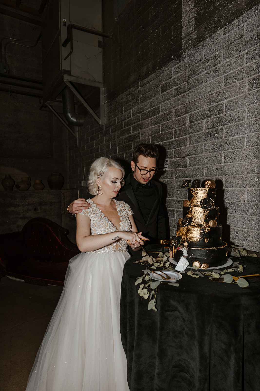 bride and groom cutting their spooky black and gold cake 