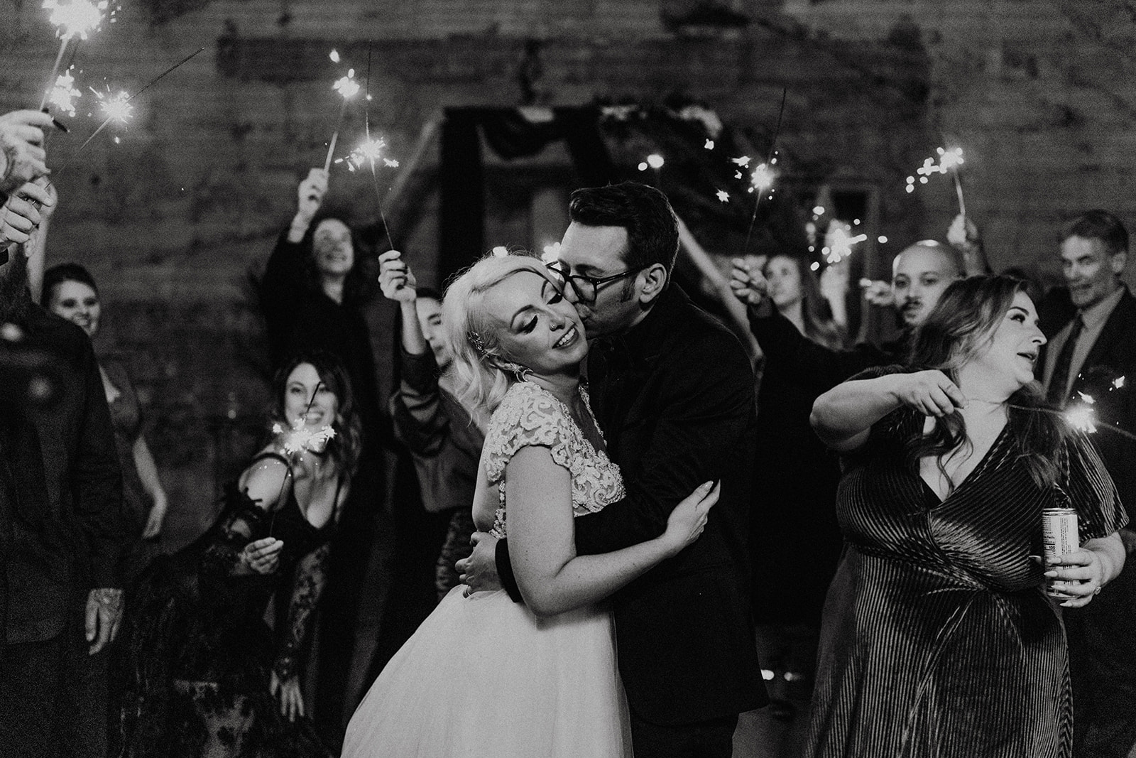 black and white of bride and groom kissing at sparkler exit at fall halloween wedding 