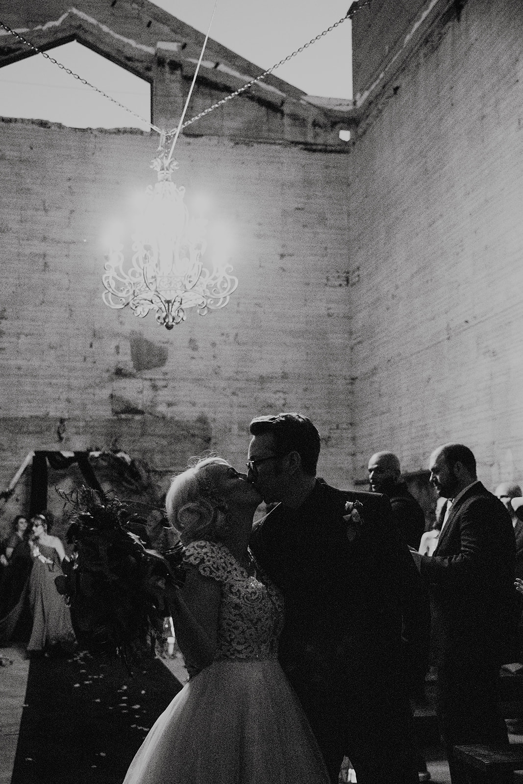 black and white of bridal couple kissing at the end of ceremony altar