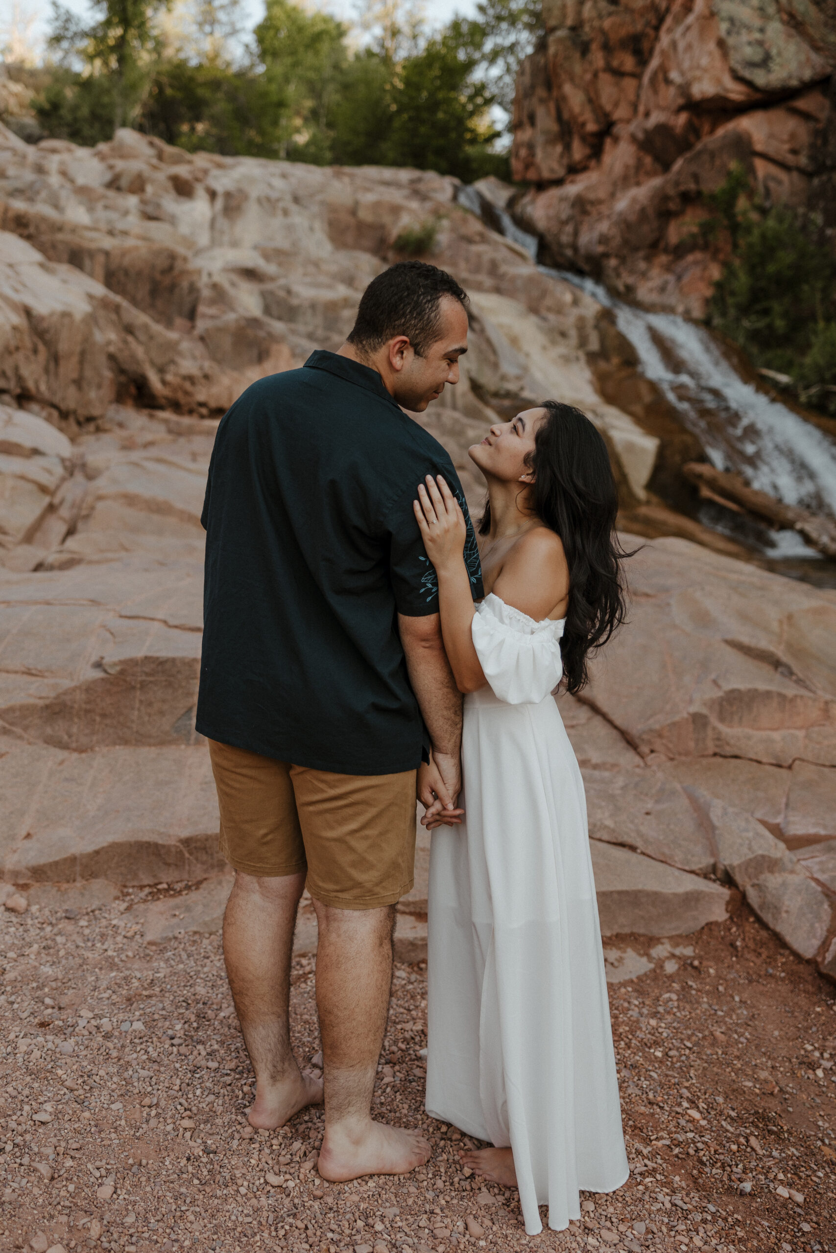 engaged couple looking at each other in front of waterfall at engagement photos