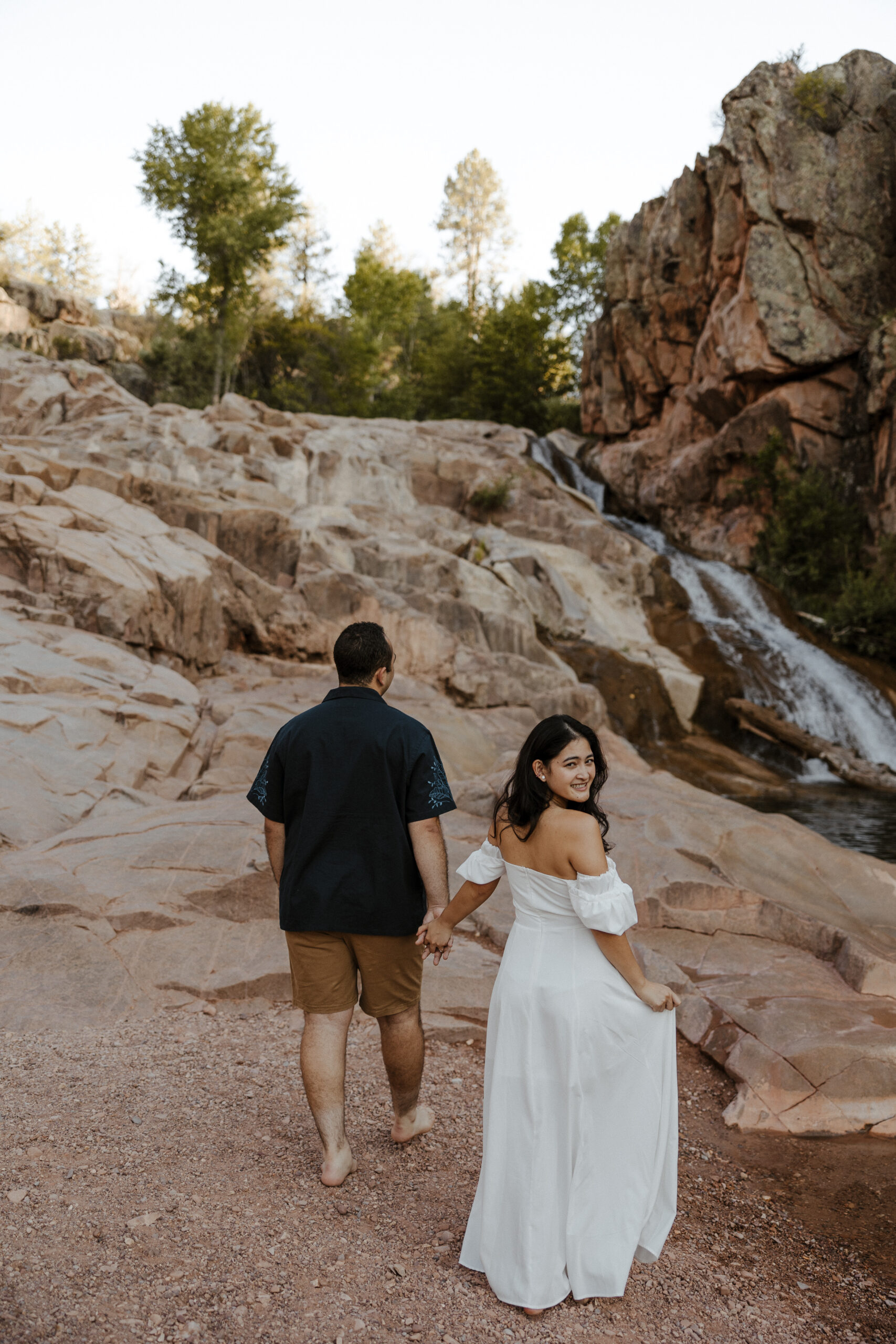 engaged couple walking towards waterfall at engagement photos