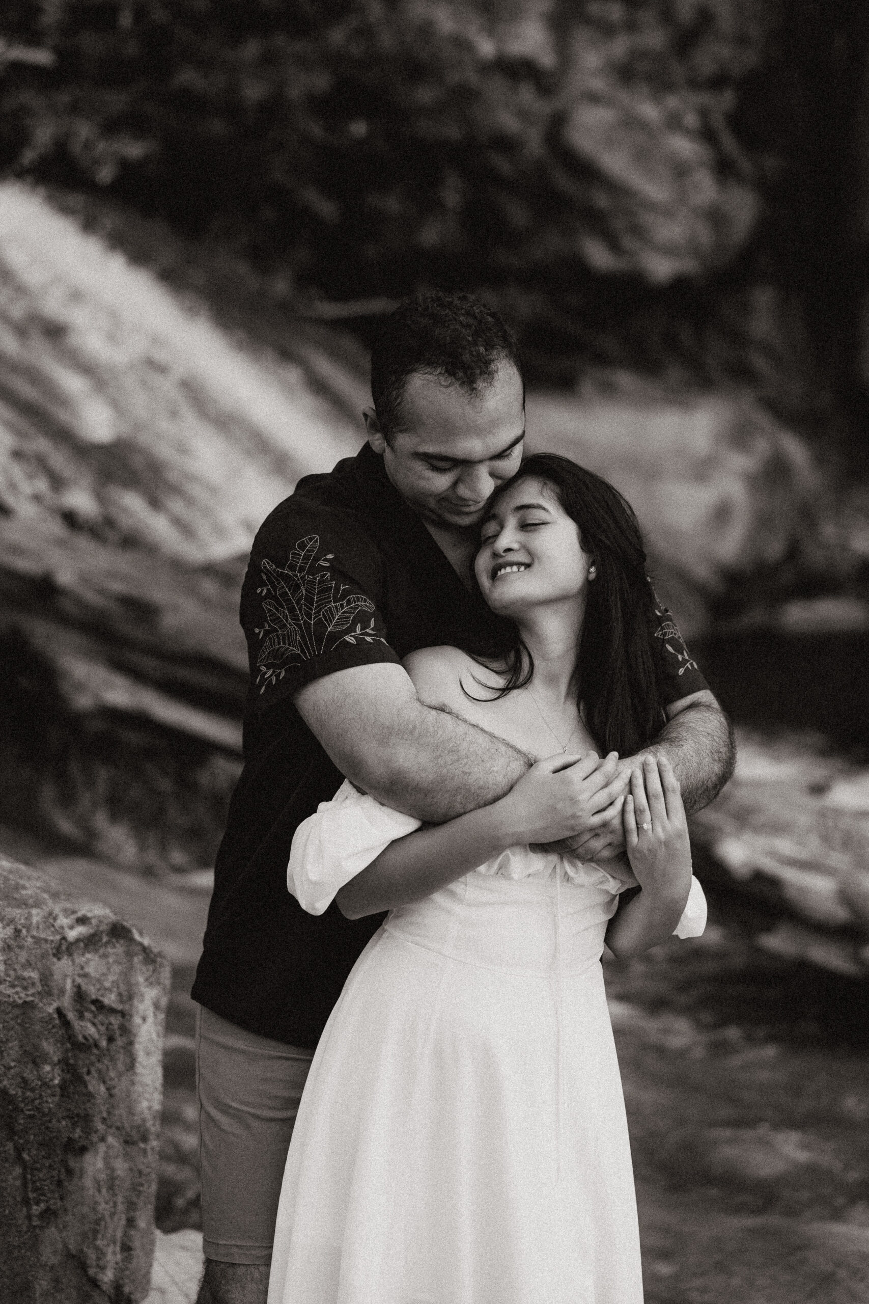 black and white of engaged couple holding each other in front of waterfall at engagement photos