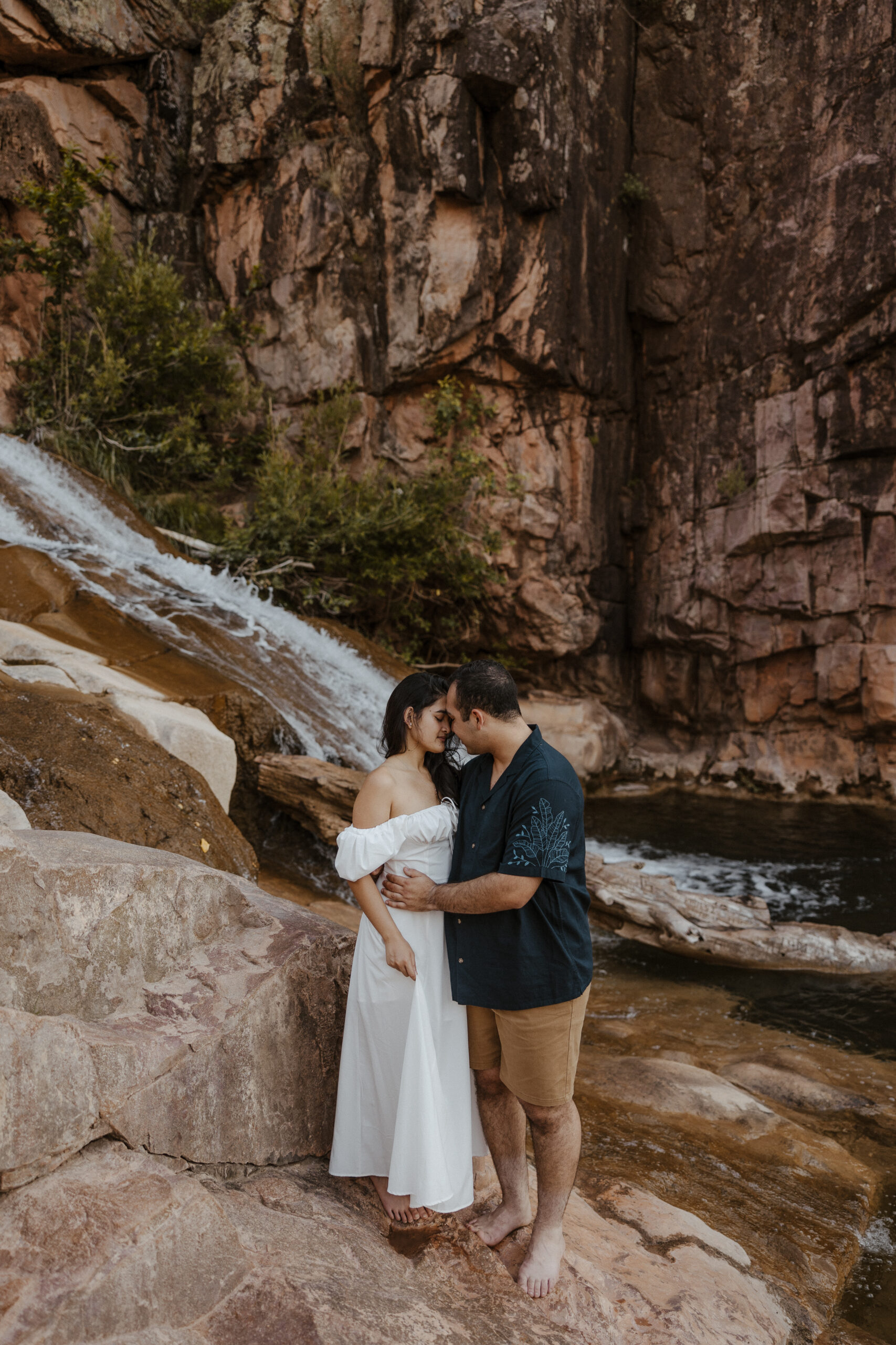 engaged couple holding each other in front of waterfall at engagement photos