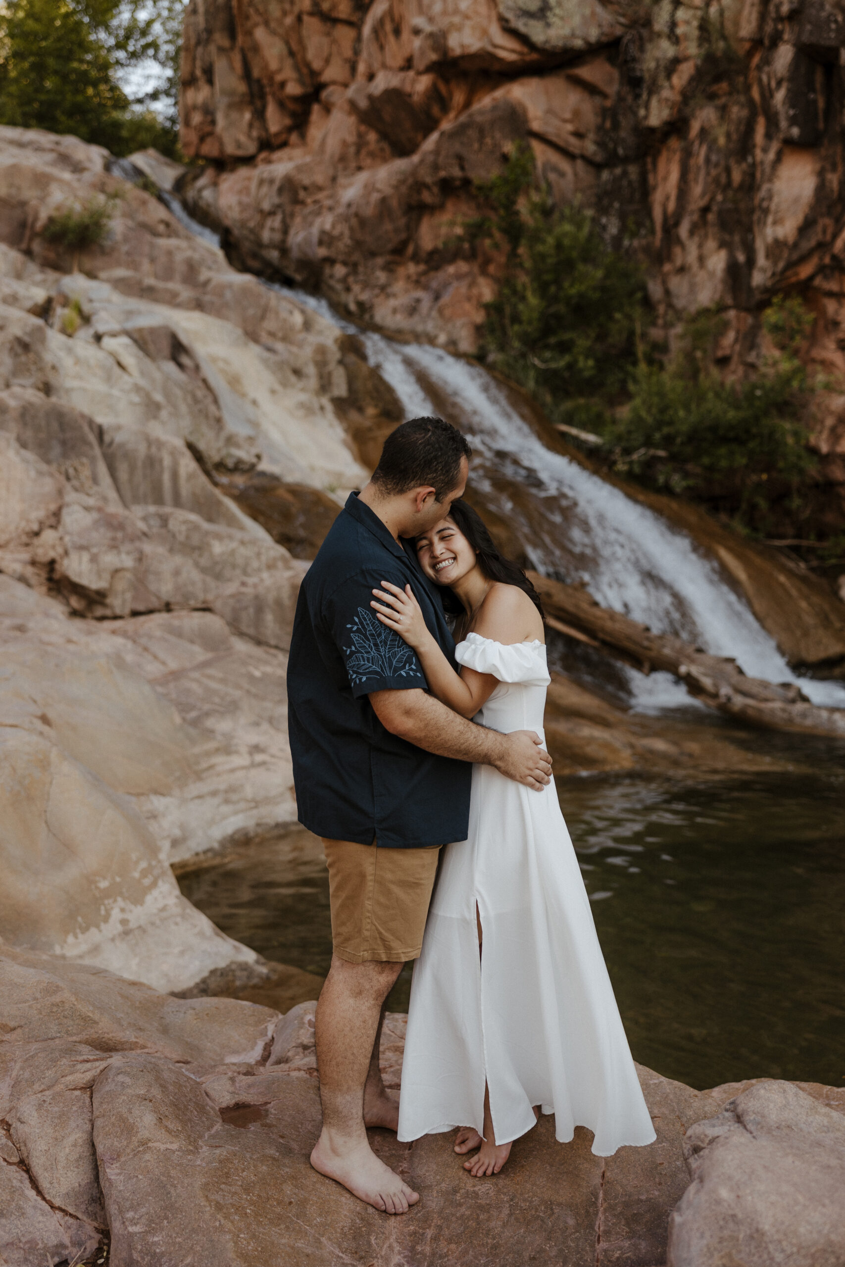 engaged couple embracing in front waterfall at engagement photos