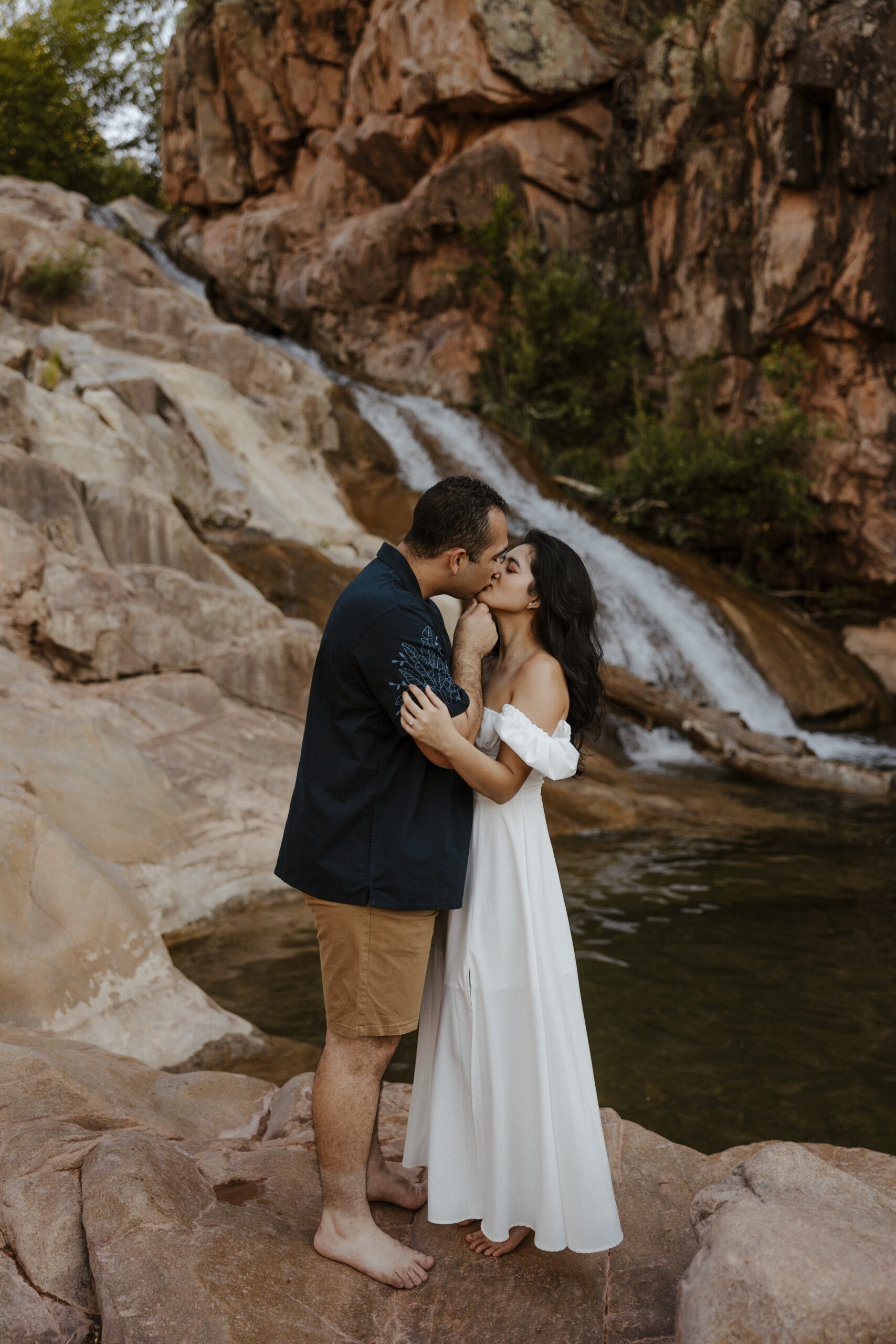 engaged couple kissing in front waterfall at engagement photos