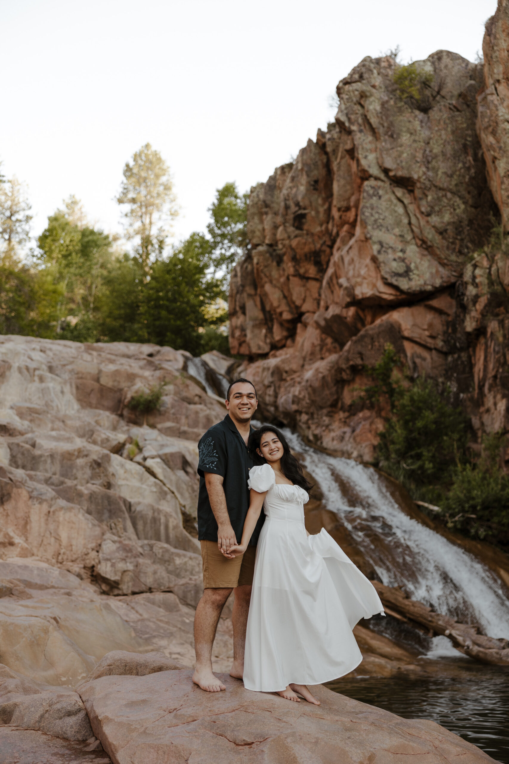 engaged couple standing in front of waterfall at engagement photos