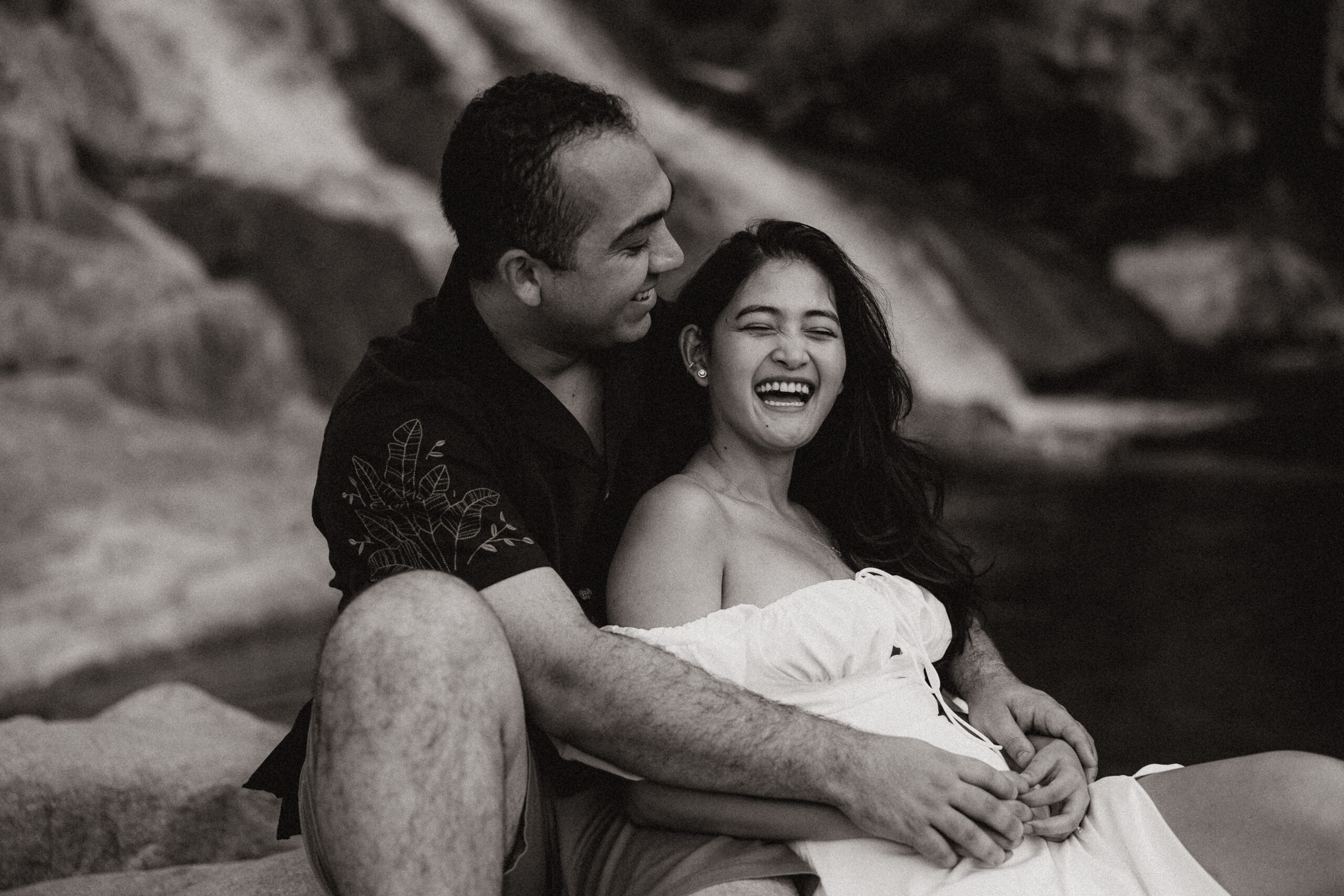 engaged couple holding each other and laughing in front waterfall at engagement photos