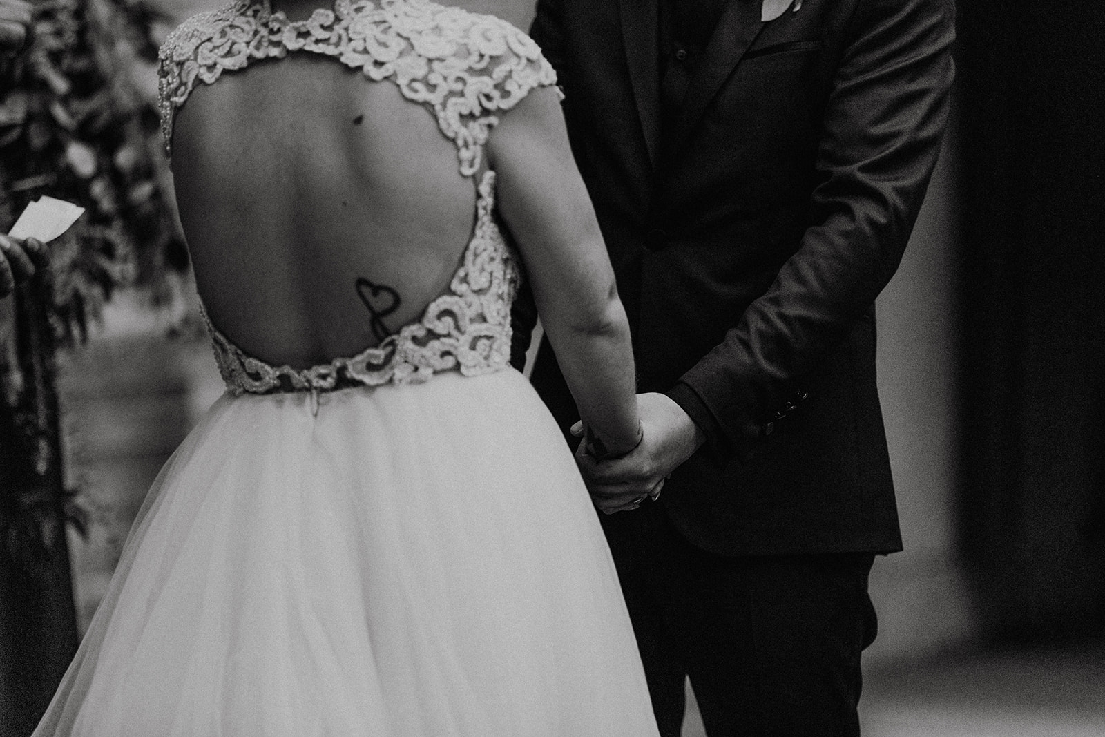 black and white of bridal couple holding hands at the altar at fall halloween wedding 