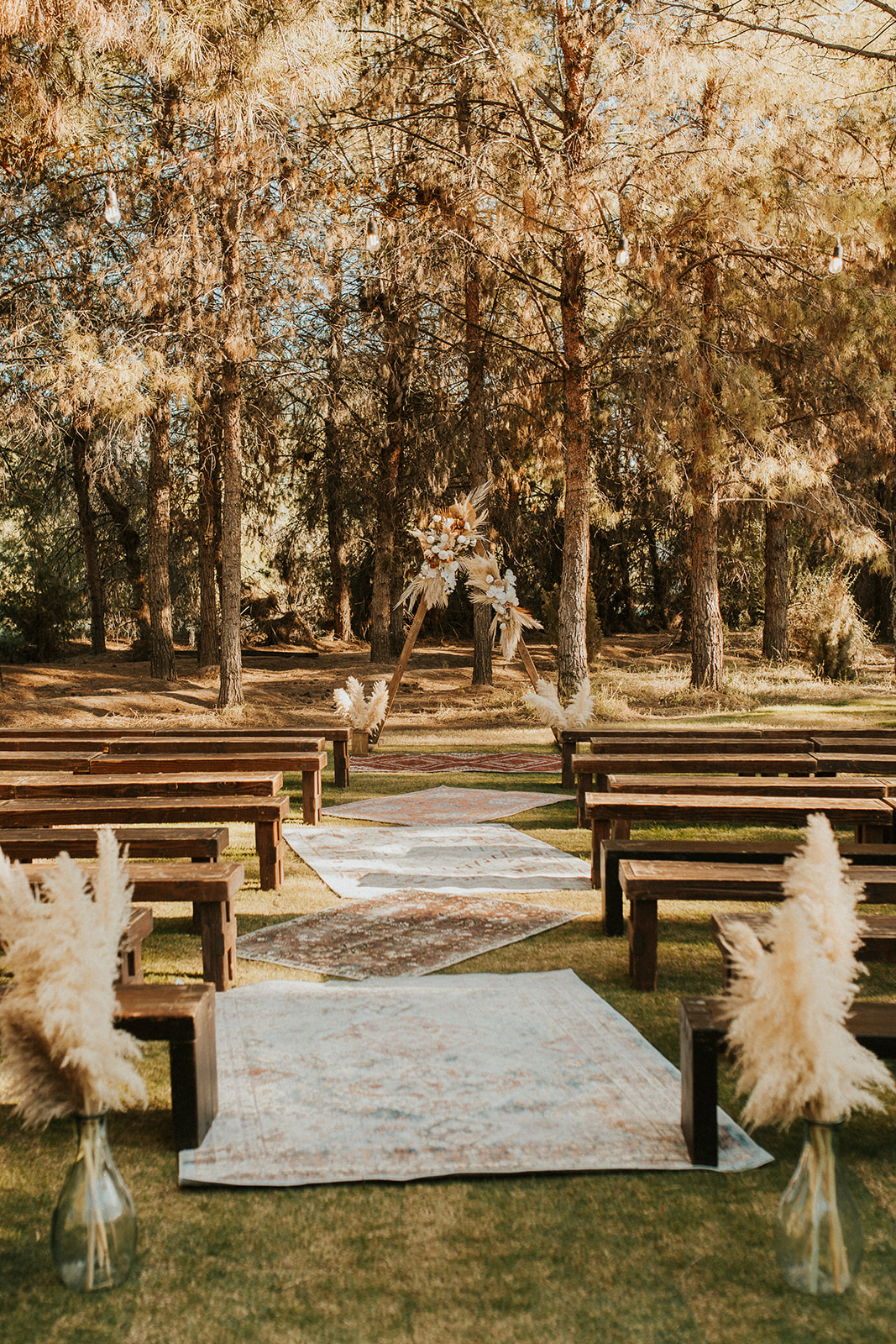 boho ceremony aisle with rugs and dried floral altar 