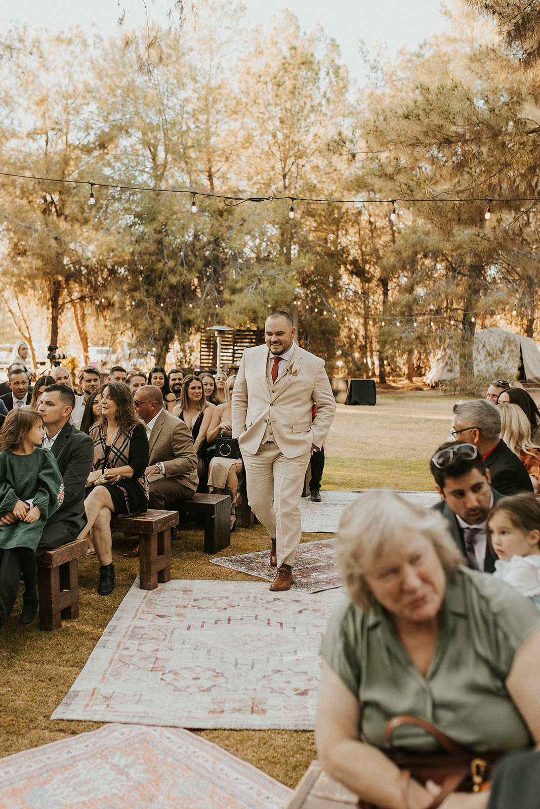 groom walking down boho ceremony aisle at one of Arizona's forest wedding venues