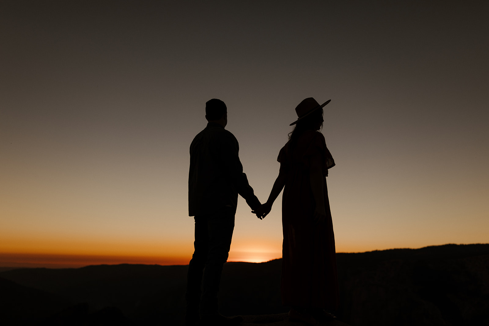 silhouettes of the couple walking at night with the last parts of sunset 