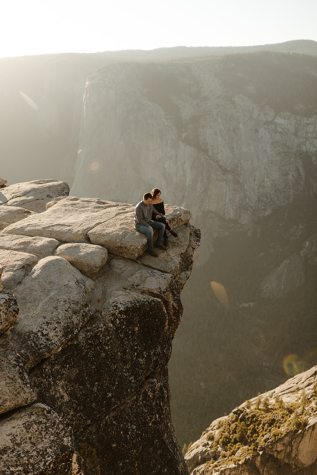 couple sitting on edge of Taft Point in Yosemite Park