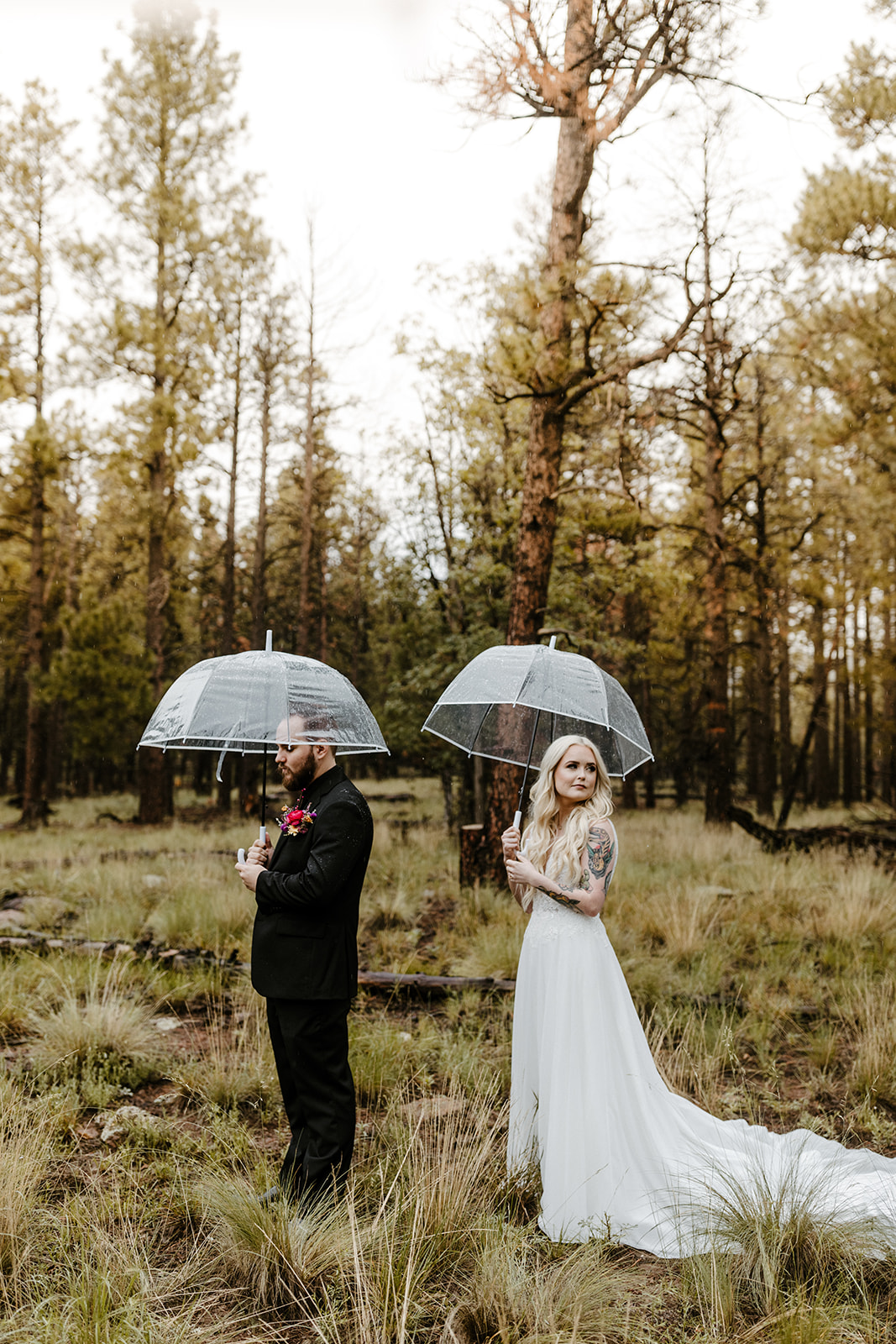 bridal couple holding umbrellas at first look on rainy wedding day