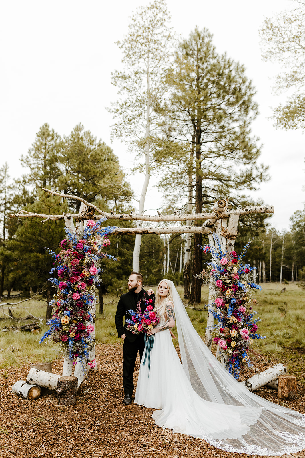 bridal couple in front of colorful, floral altar at one of Arizona's forest wedding venues
