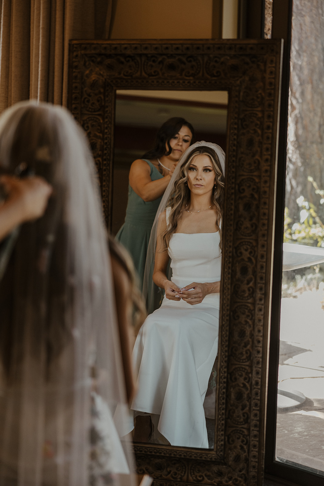 mother of bride helping with her hair while bride looks in the mirror 