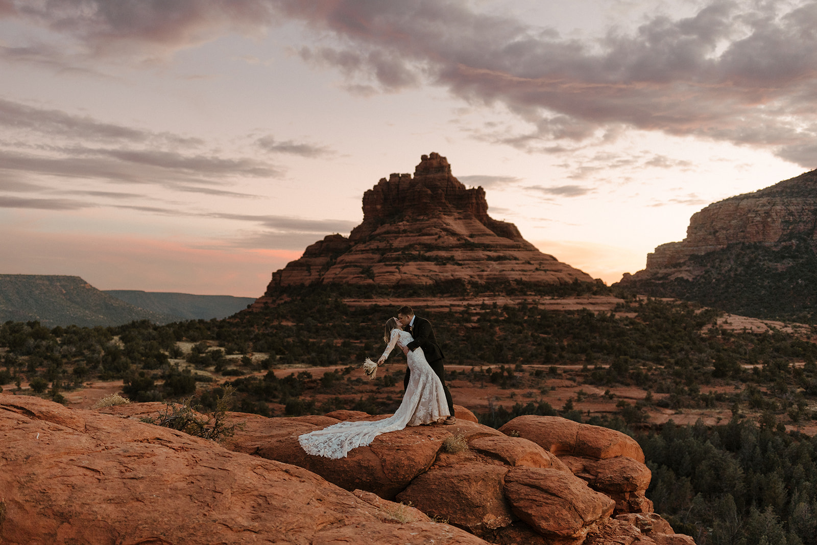 groom dipping and kissing bride during sunset at sedona elopement wedding 