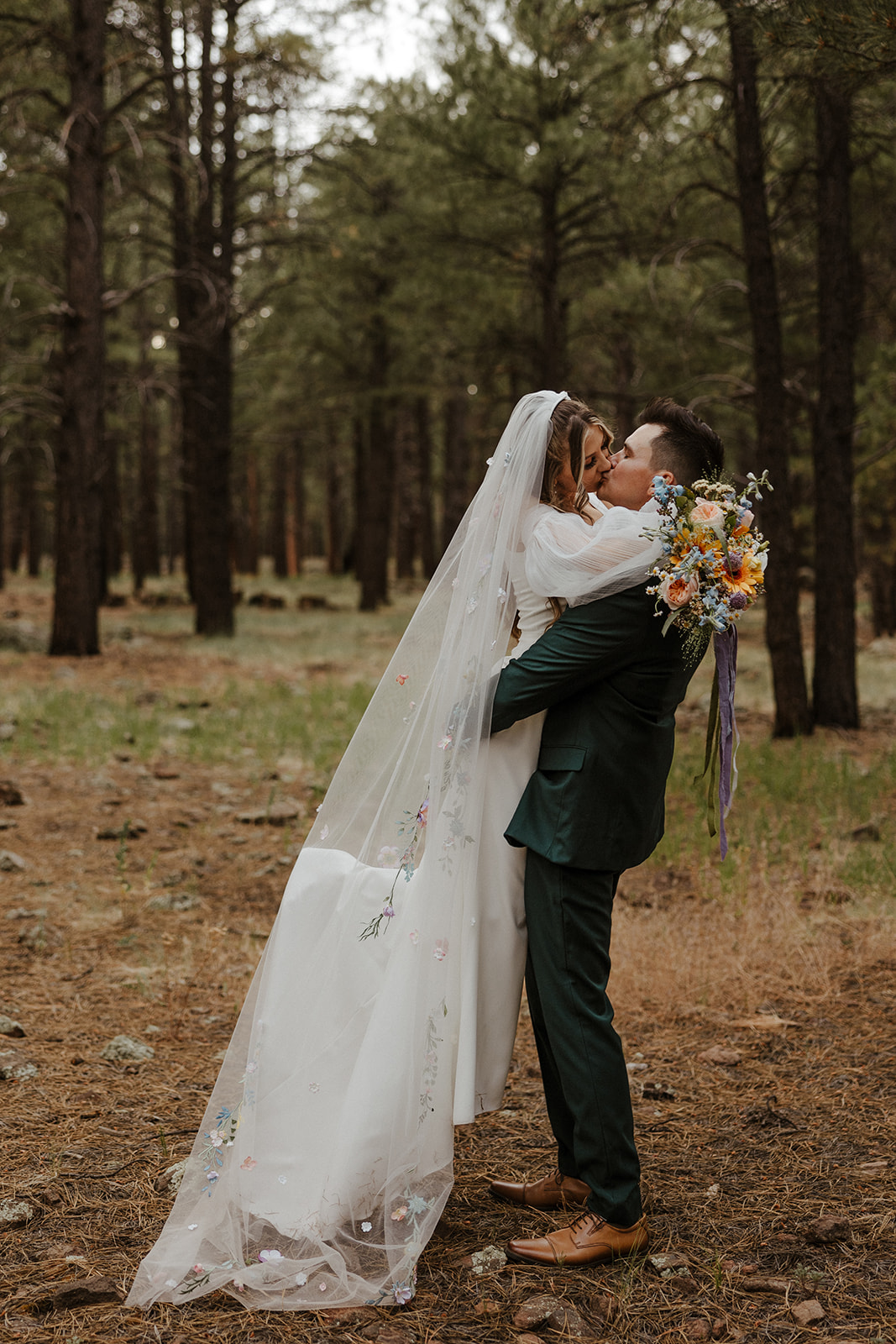 bride and groom kissing in the woods 