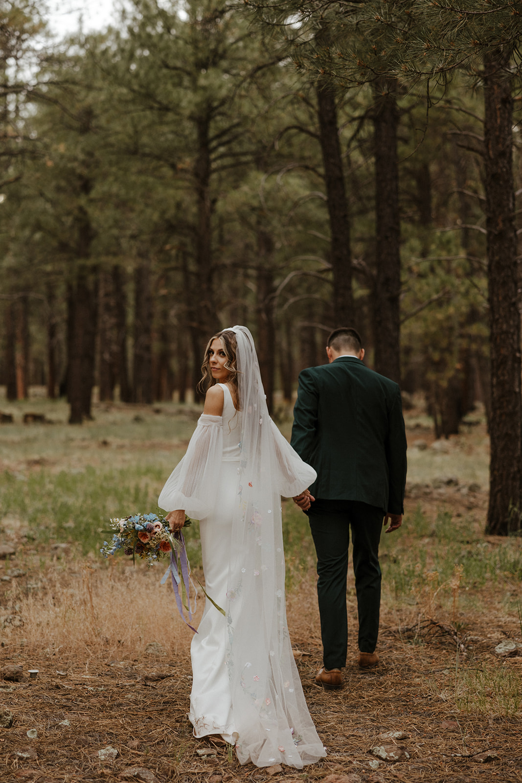 bride and groom walking into the woods 