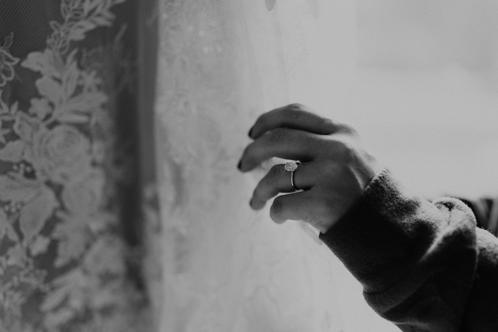 detail black and white shot of bride's hand holding her dress 