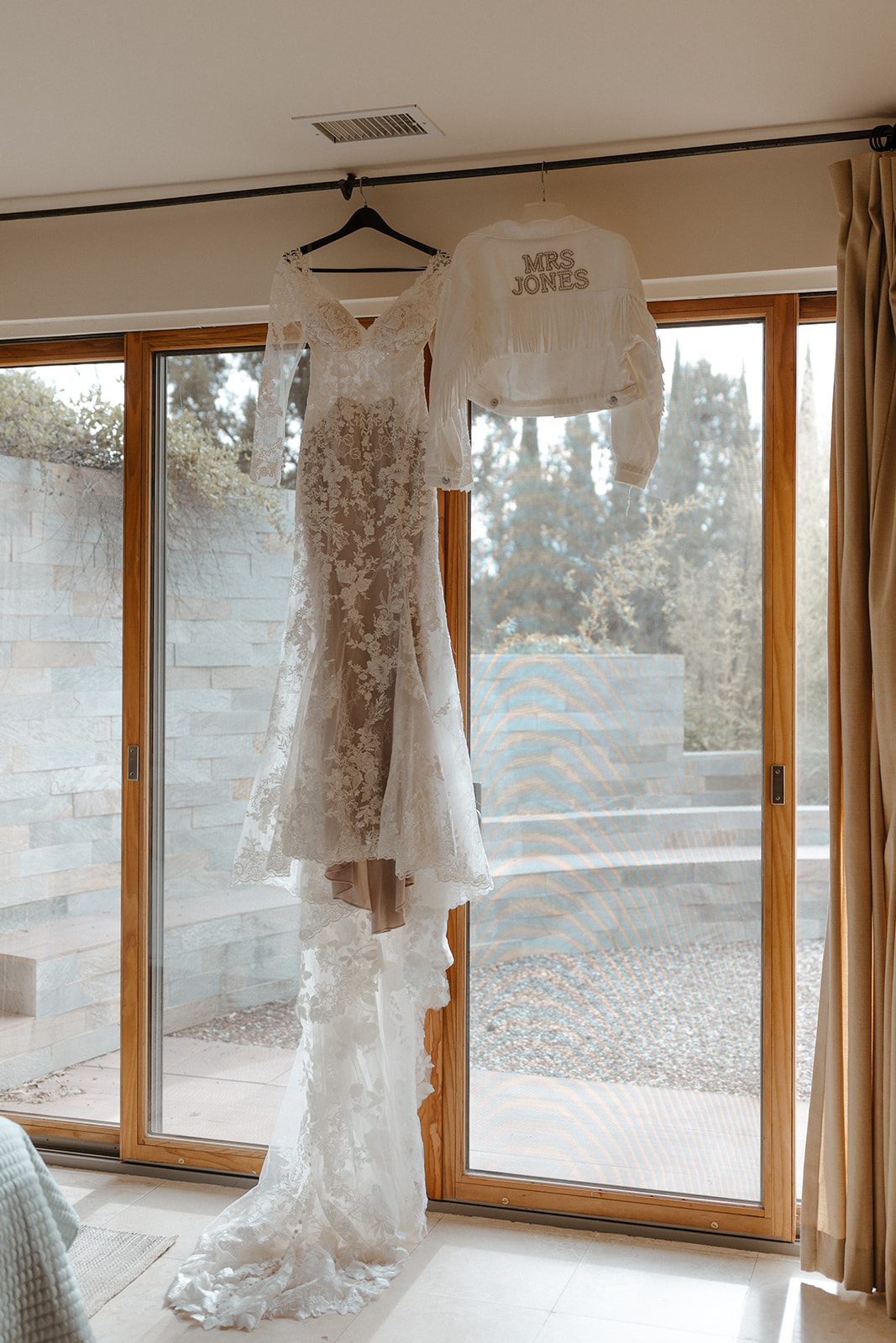 bride's dress and jacket hanging while she is getting ready