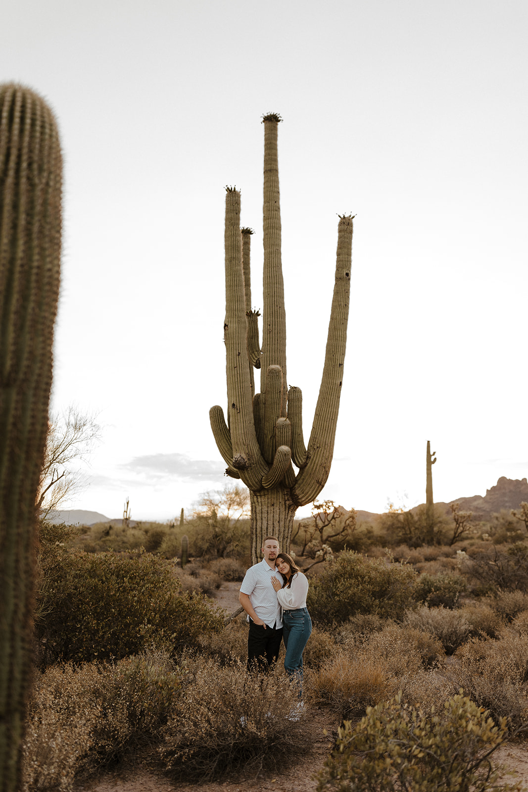 couple posing in front of a giant cactus at lost dutchman state park in az