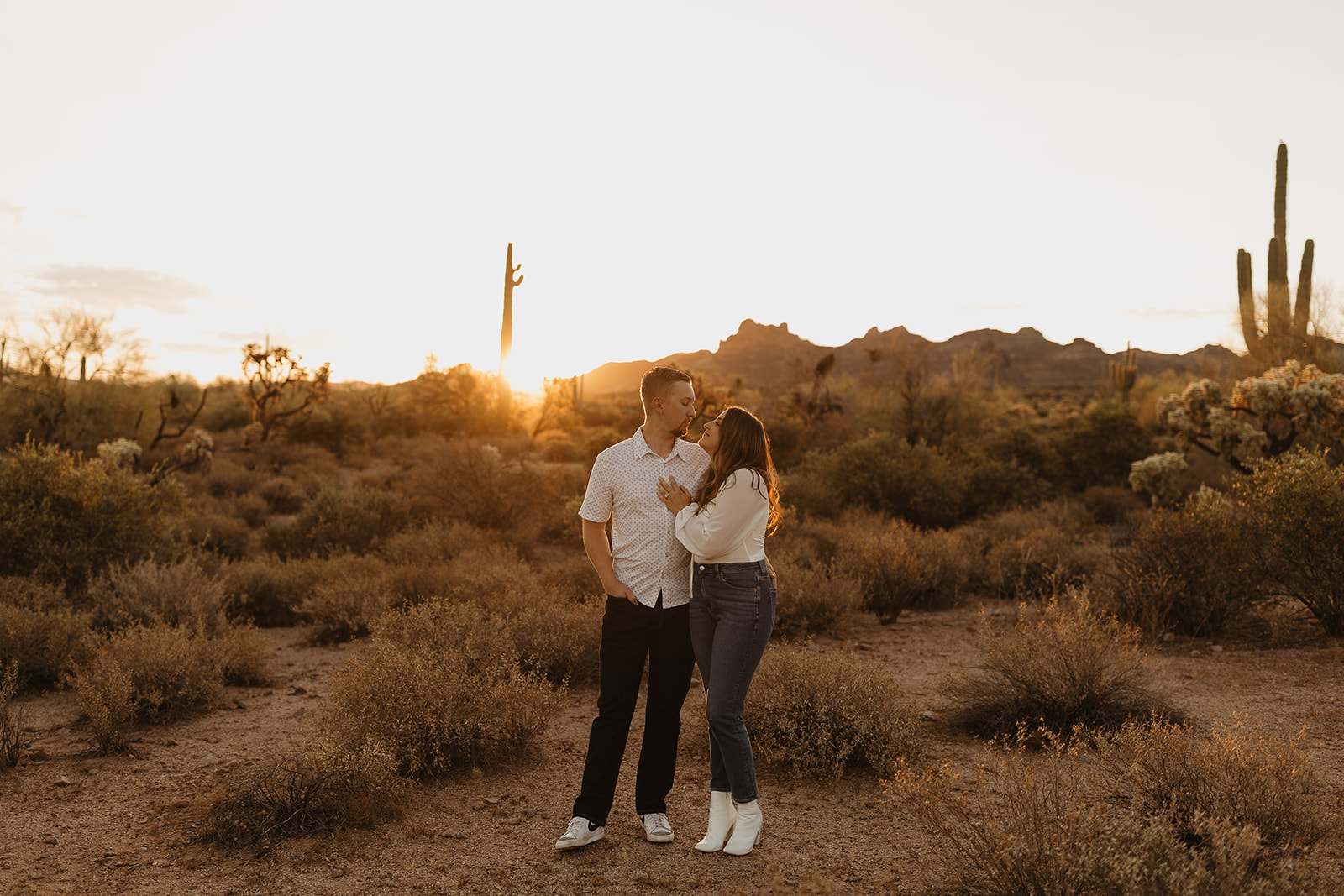 engaged couple looking each other as the sun is rising at lost dutchman state park