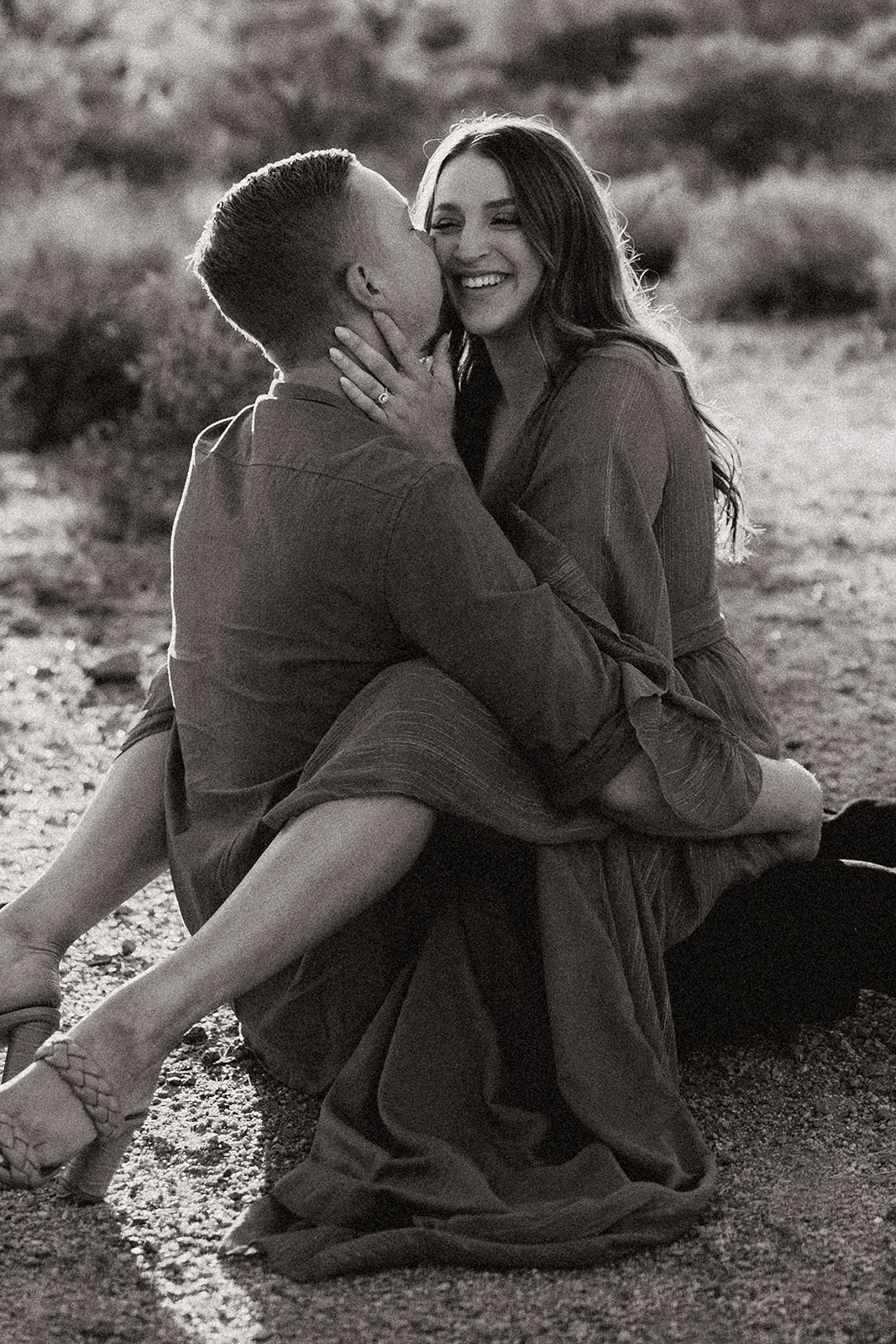 black and white of fiance sitting on groom to be at lost dutchman state park