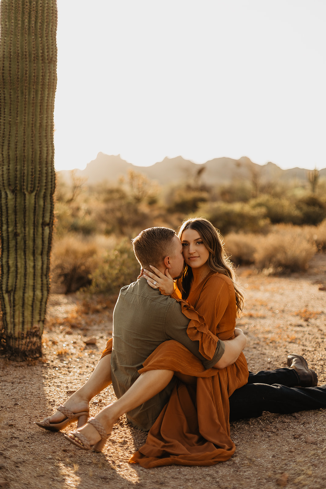 fiance sitting on groom to be as the sun is rising at lost dutchman state park
