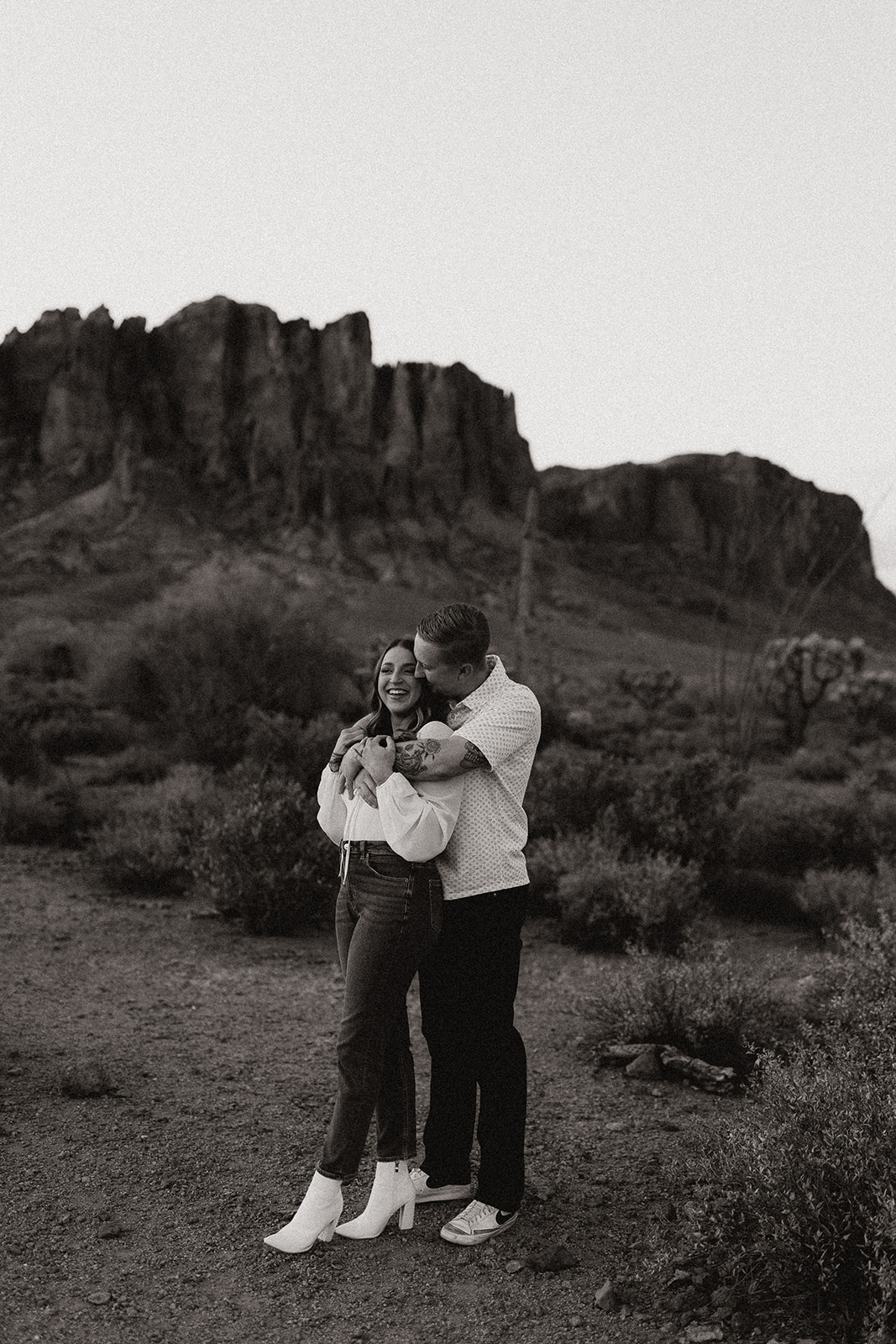 fiance holding bride to be from behind kissing her face at lost dutchman state park az