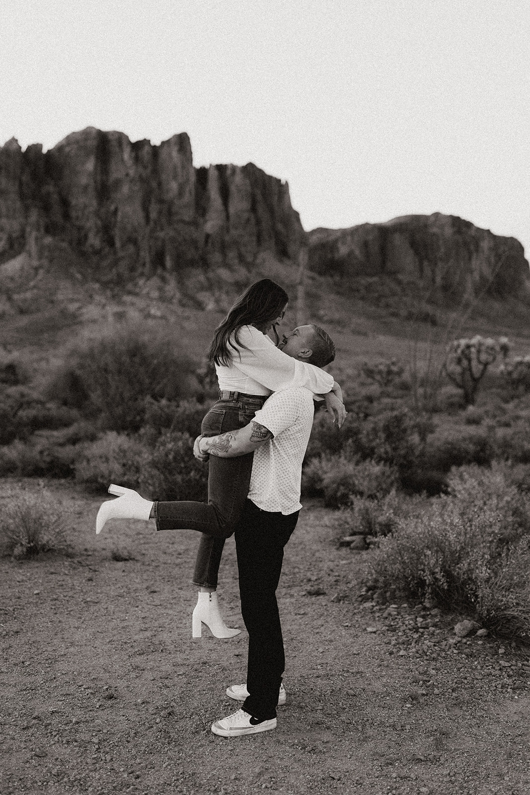 black and white of engaged couple holding each other at lost dutchman state park
